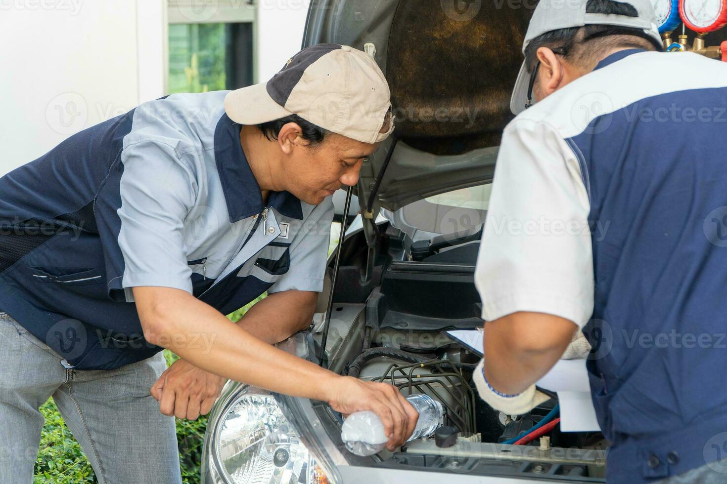 two Auto repairman checks the engine and cooling system before traveling on a long holiday. Concept of Car care and maintenance from experts, Coaching, and advice For practicing a car from an expert photo