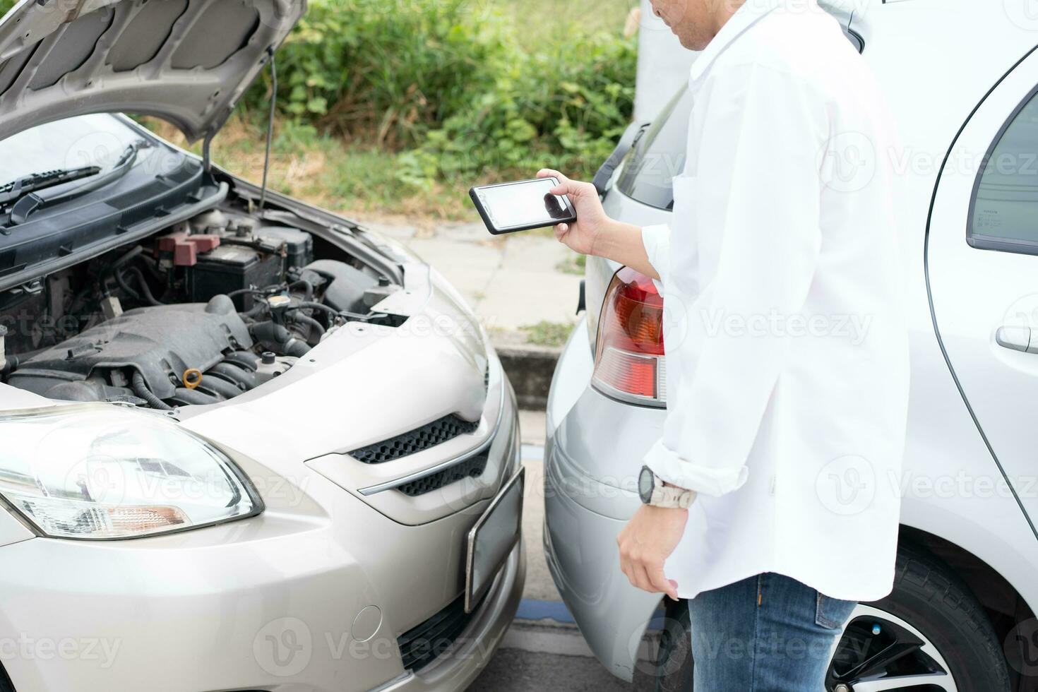 Asian men driver check for damage after a car accident before taking pictures and sending insurance. Online car accident insurance claim after submitting photos and evidence to an insurance company.