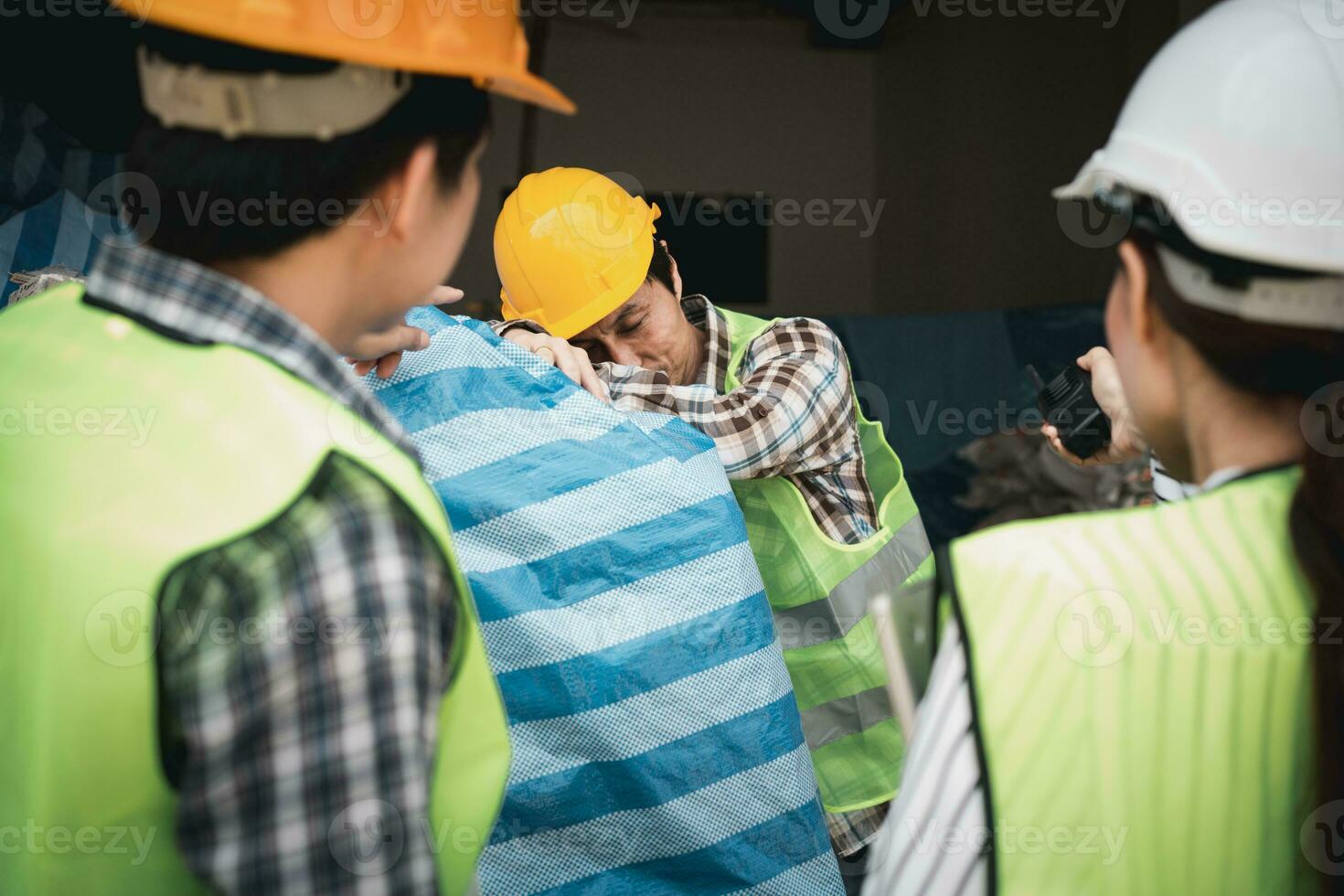 Foreman user radio to nurse for first aid Construction worker faint in construction site because Heat Stroke. Worker with safety helmet take a nap because so are tired from working in the hot sun photo