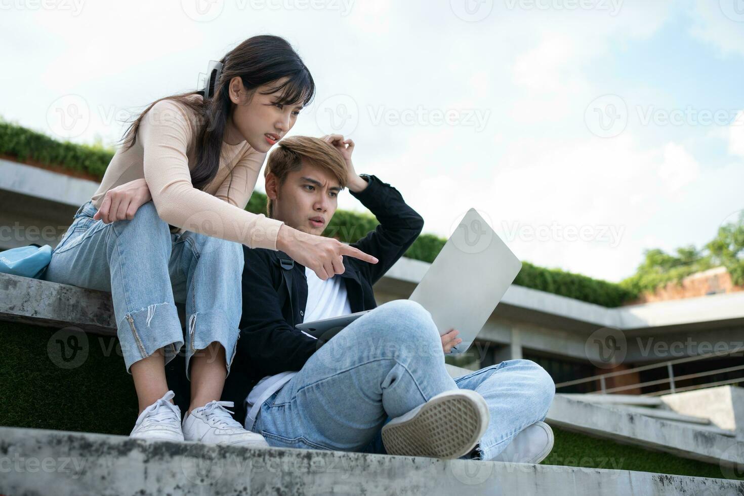 Asian students sitting on steps and use computer laptops to discuss before exams, Student lifestyle at university. Group of student do a project together photo