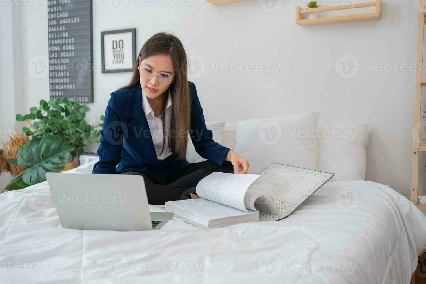 Overworked and Stressed young Asian woman working on laptop computer and document paper in bed at hotel, Business trip, Burnout, technology, copy space, Professional Burnout And Exhaustion Concept. photo