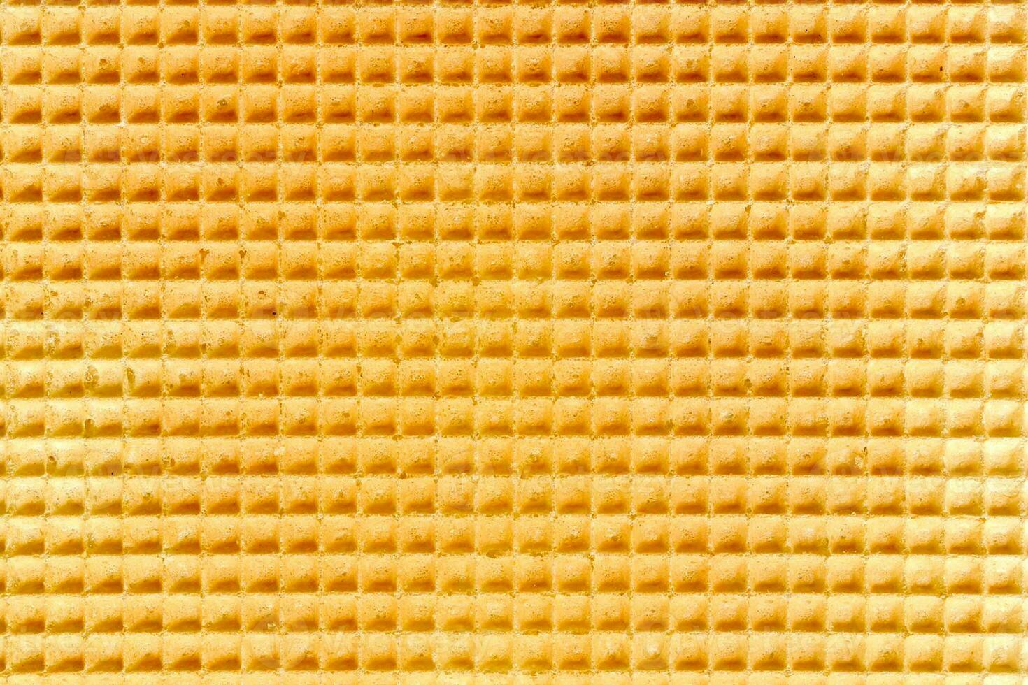 Waffle relief texture background. Sweet tasty dessert. Empty golden waffle texture, background for your design with copy space. Close-up pattern of a traditional Dutch waffle as a background. photo