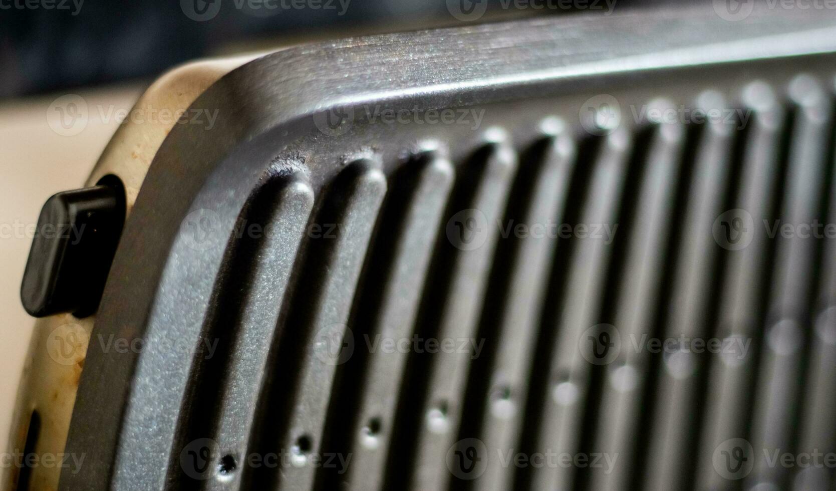 Black electric grill grate, textured background. The surface of the electric grill. Pollution of the surface of the electric stove. Close-up of a home electric grill, in the kitchen. BBQ. photo