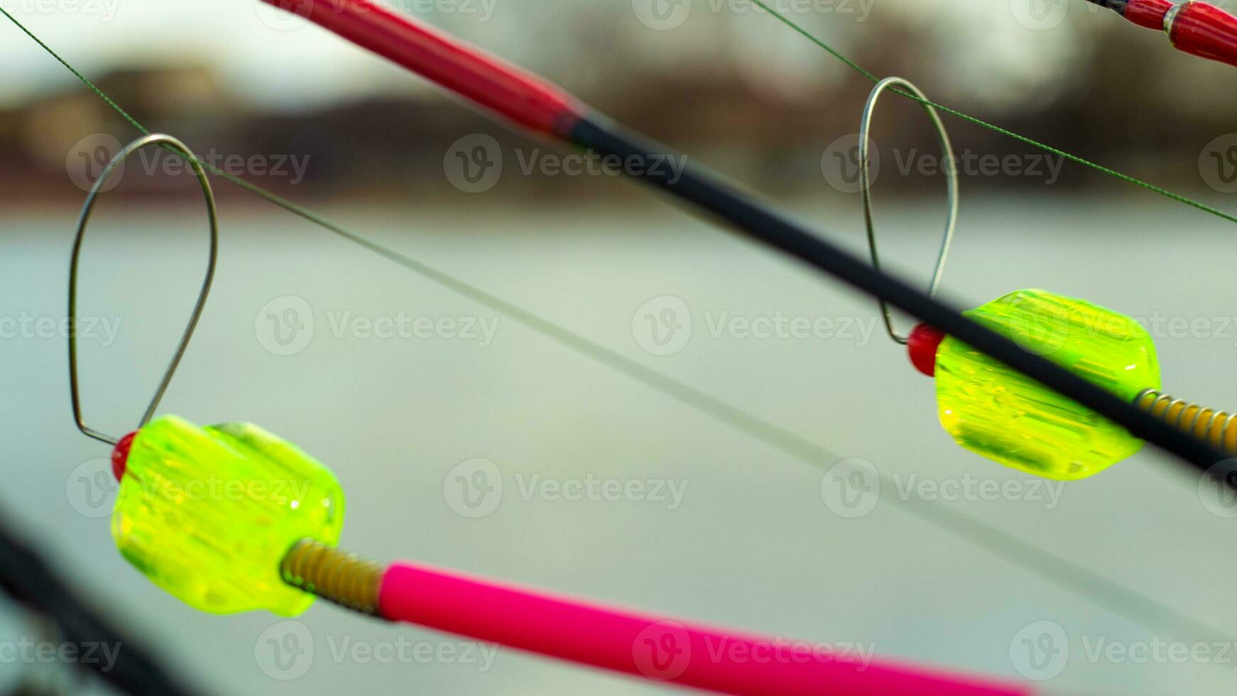 The bite alarm hangs on a fishing rod against the background of water. Fishing rod while fishing on the lake, river. Fishing tackle. Carp rod on a stand with a bite alarm on the line. photo