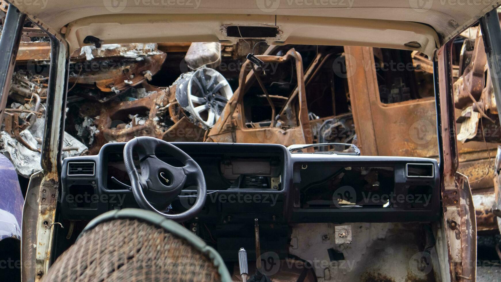 A lot of burnt fired cars in the parking lot, the consequences of the invasion of Ukraine. War in Ukraine. Cemetery of destroyed cars of civilians who tried to evacuate from the war zone. photo
