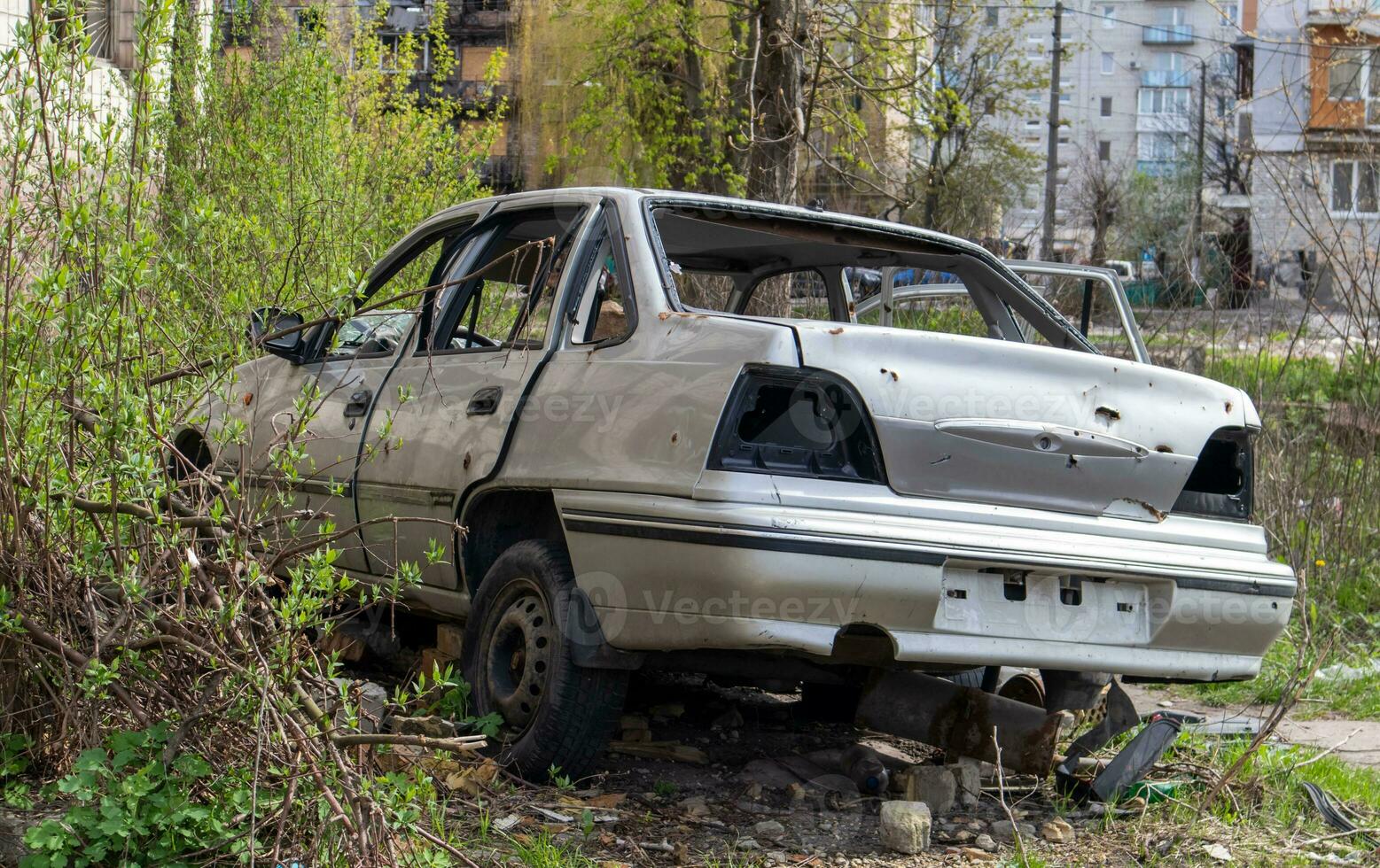 A broken Ukrainian civilian car, shot by artillery, stands in the courtyard of a destroyed house. War between Russia and Ukraine. The wreckage of an abandoned car. photo