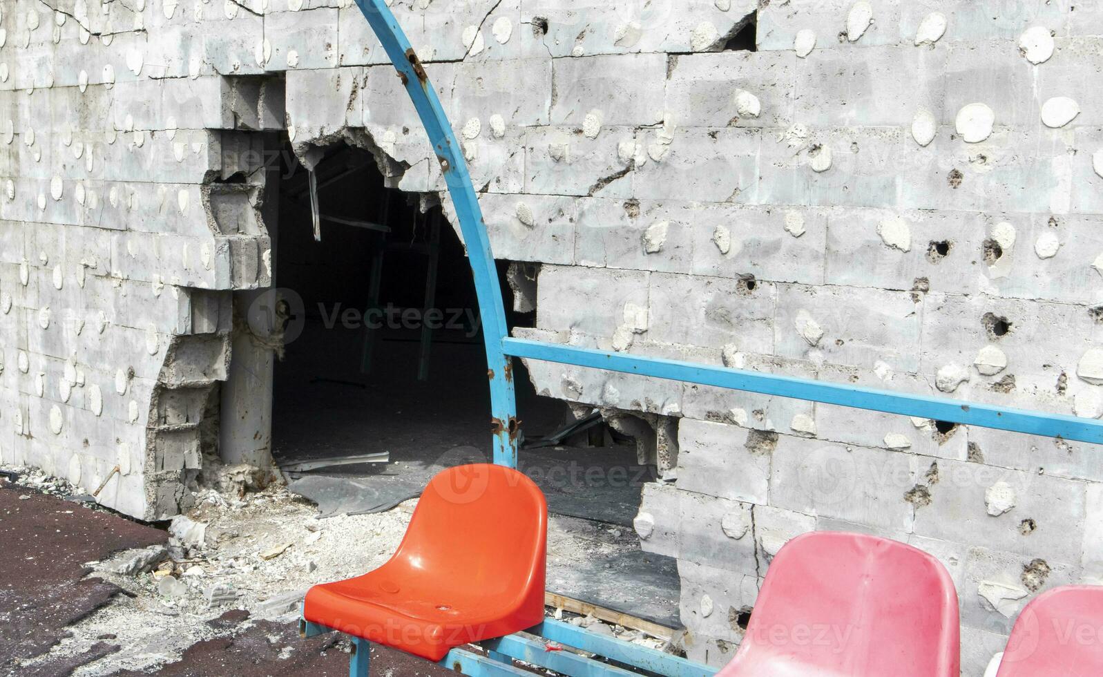 War in Ukraine. Broken plastic benches for fans on the podium, in a destroyed football stadium in a children's football school. The consequences of shelling from artillery. photo