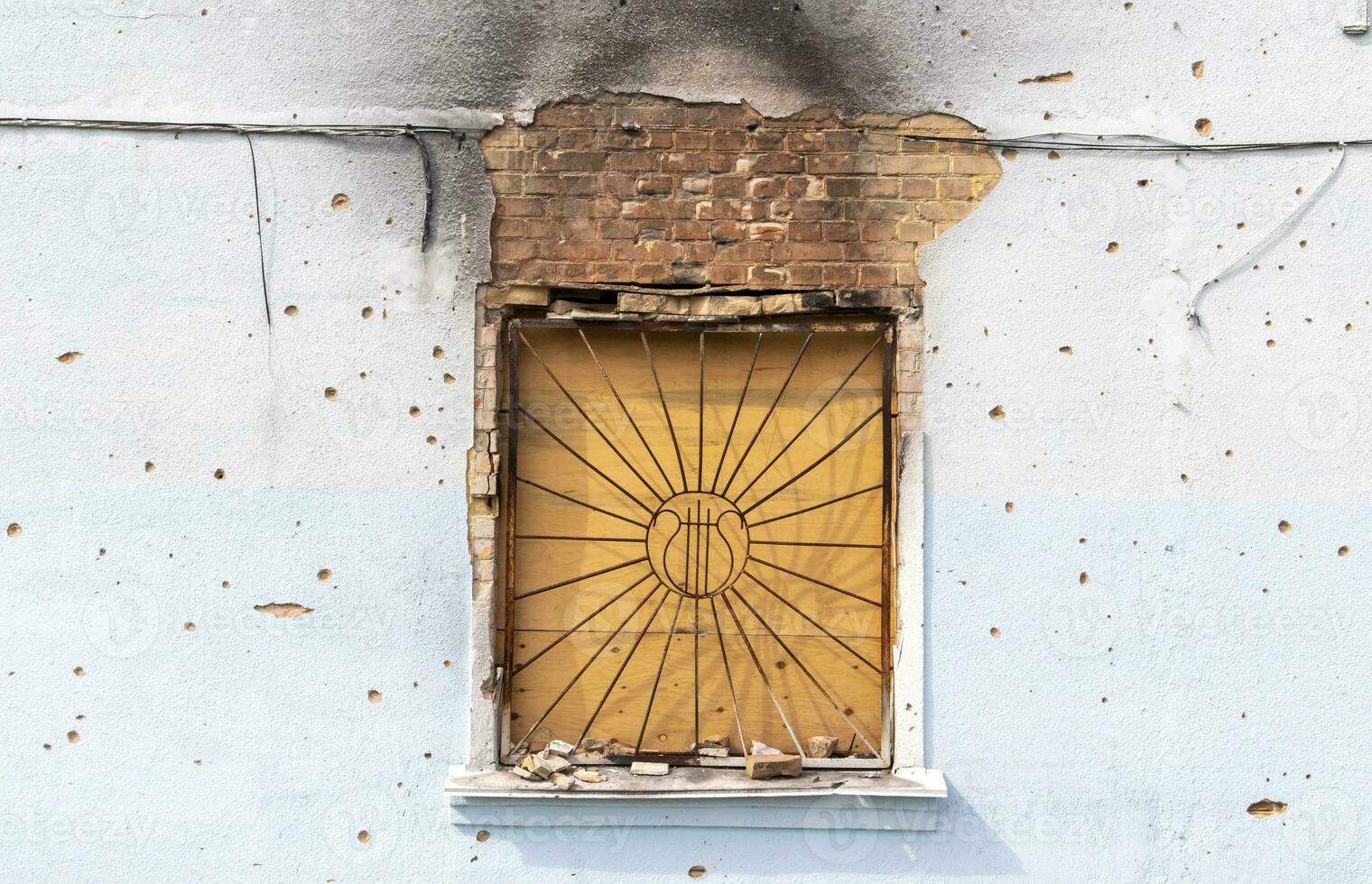 The buildings were hit by shelling. Boarded up windows and damaged facade. Preparing the house for hostilities and war. Destroyed houses in the city during the war in Ukraine. photo