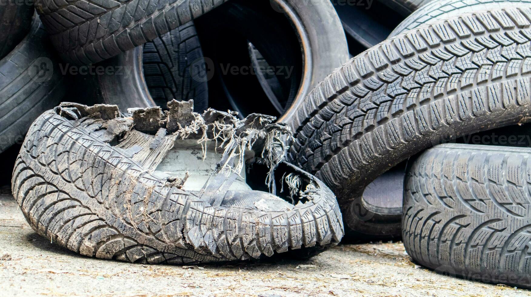 Garbage from a pile of black old car tires. Environmental pollution. Ecological problems. Old car tires thrown into an industrial landfill for recycling. Reuse of worn rubber tires. photo