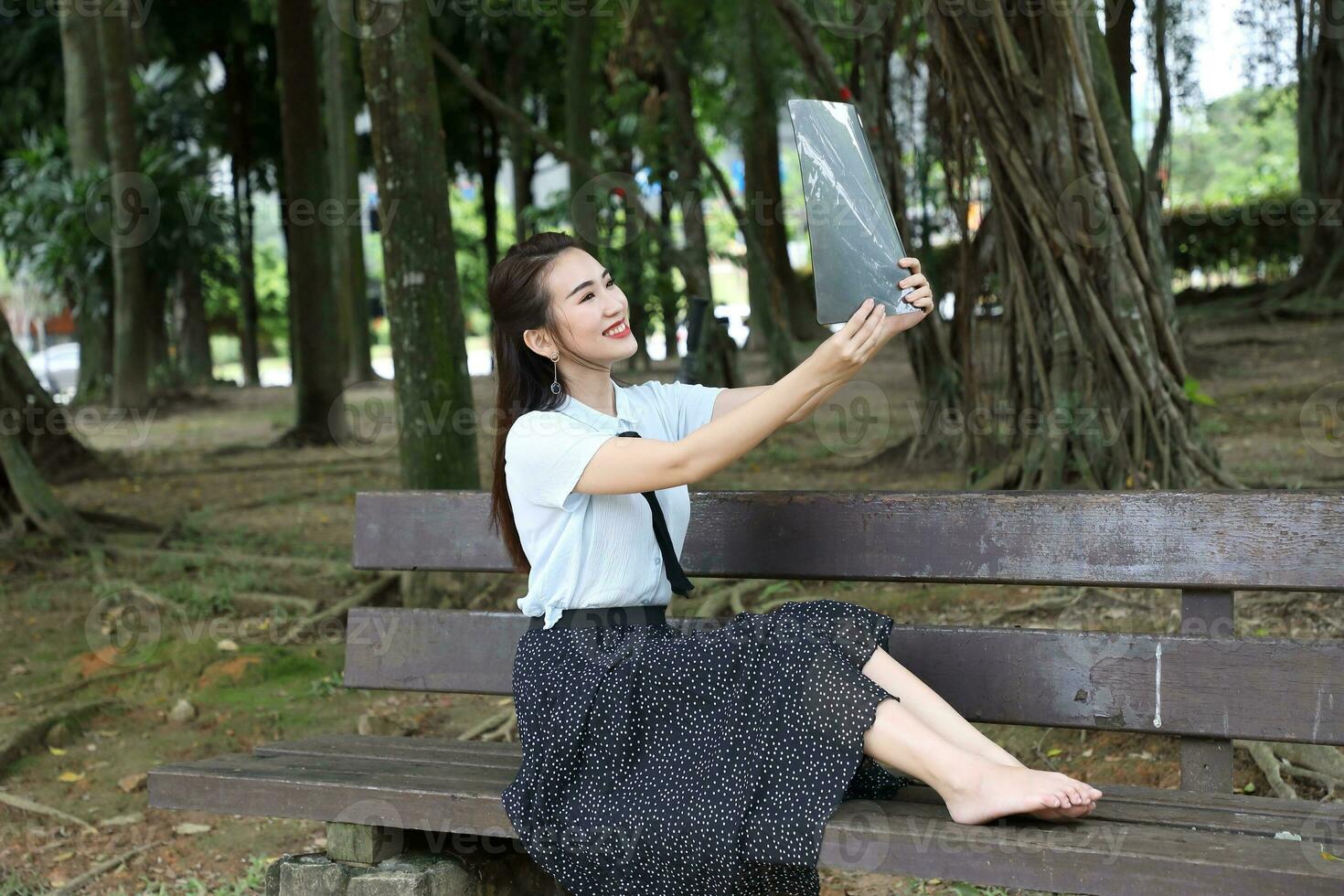 Young asian chinese woman outdoor on park bench hold file book folder read see smile photo