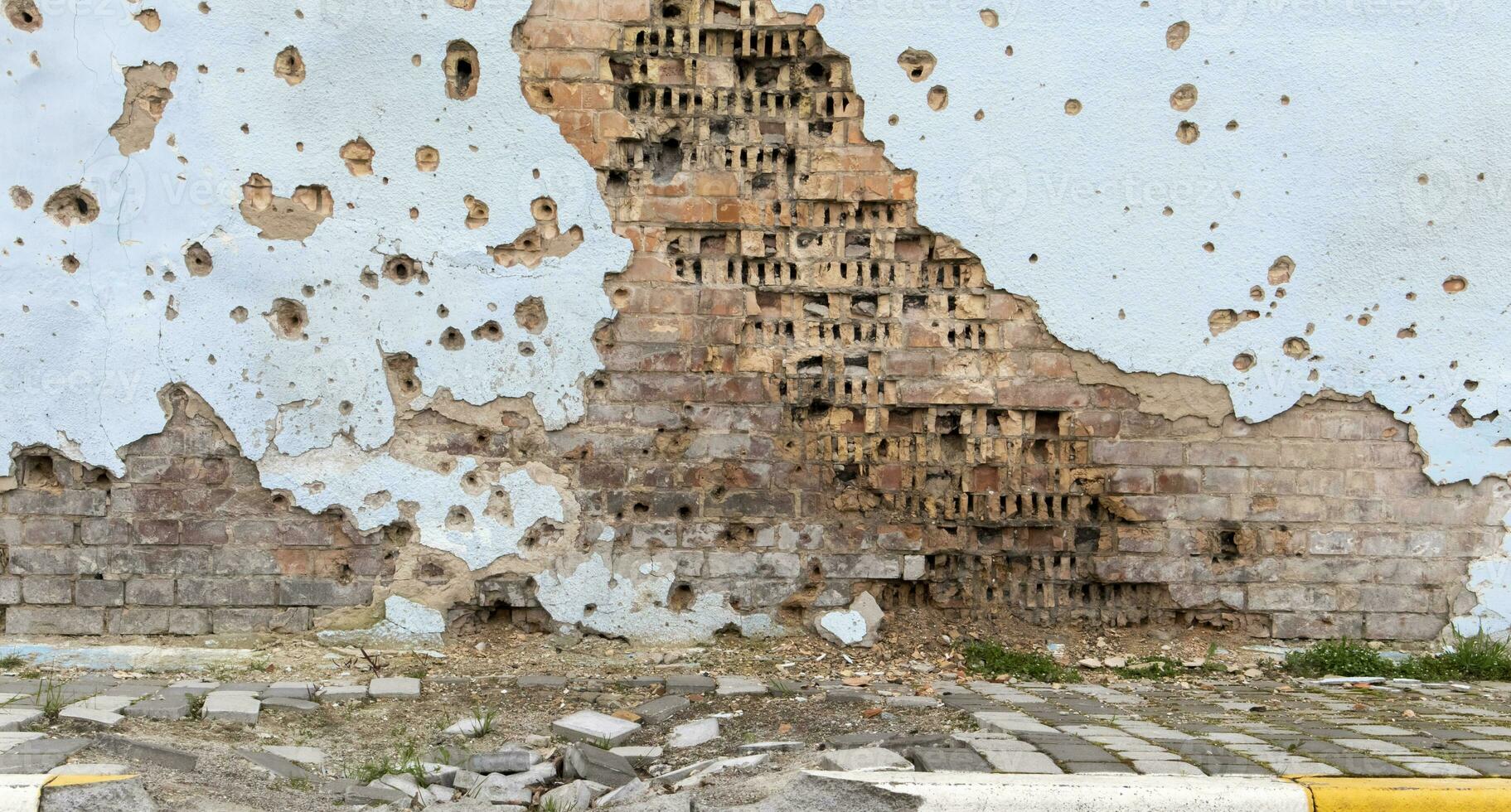 The wall of a building battered by rocket fragments in a war zone. Shelled wall. Facade of a bombed-out building. Armed conflict in Ukraine. Damage to the house as a result of artillery shelling. photo