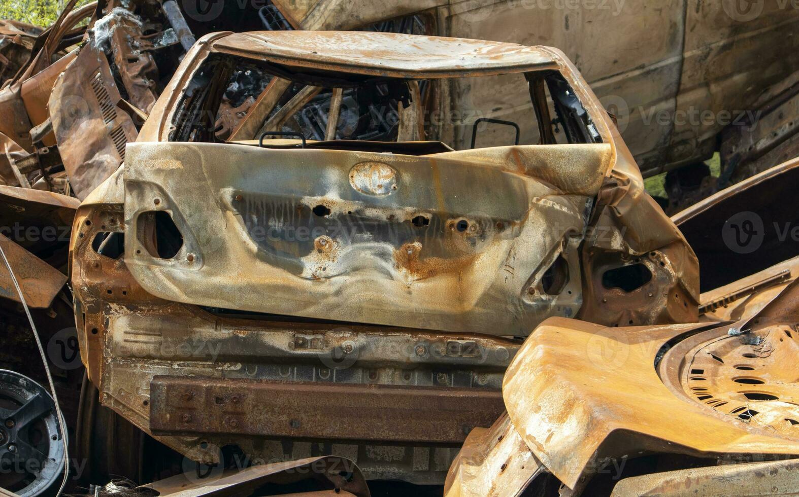 A lot of burnt fired cars in the parking lot, the consequences of the invasion of Ukraine. War in Ukraine. Cemetery of destroyed cars of civilians who tried to evacuate from the war zone. photo