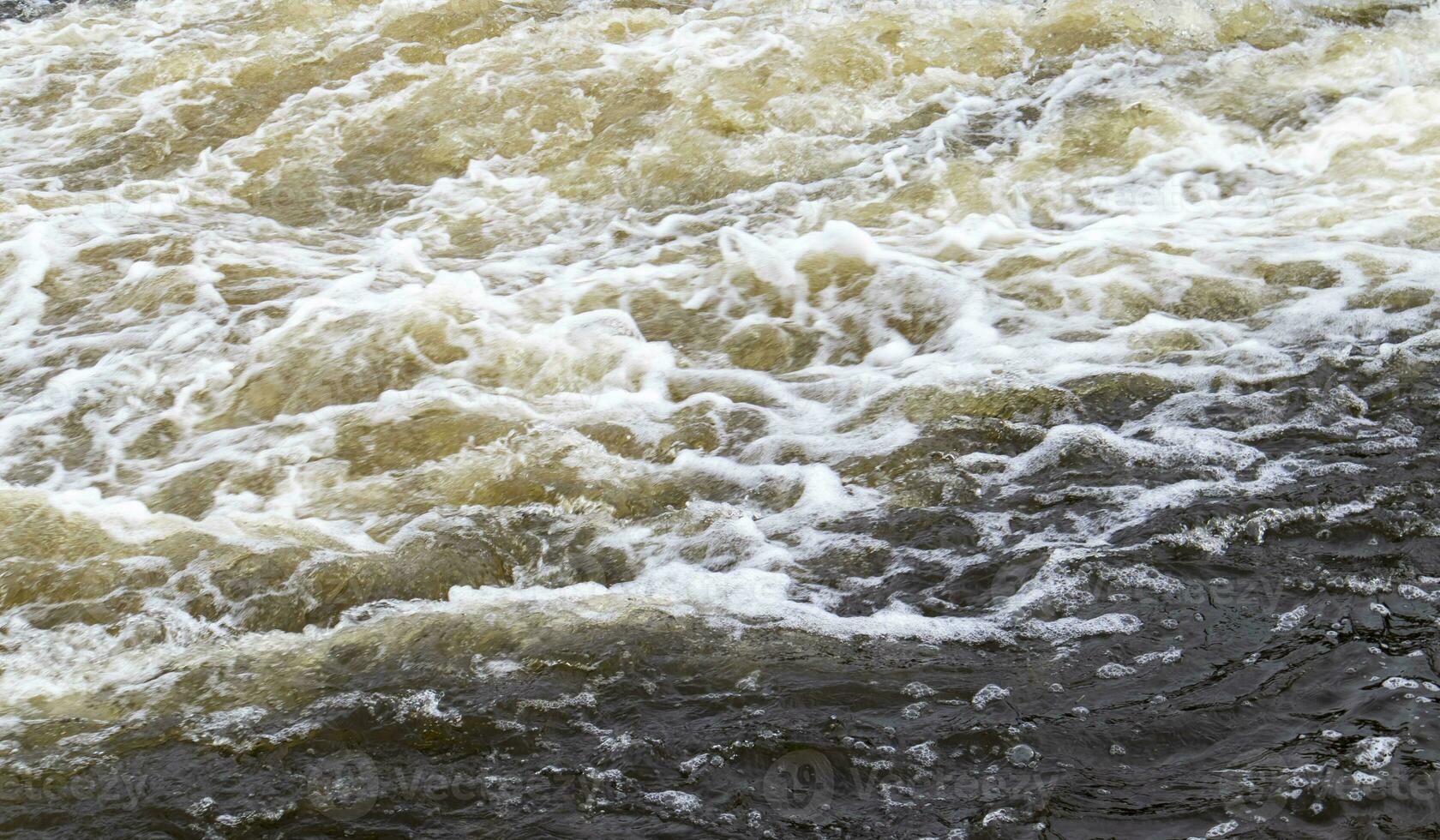 River rapids. Close up abstract background of falling water. Water flows over river rocks. A beautiful powerful stream of a stormy mountain river. The river rushes with fast-flowing water. photo