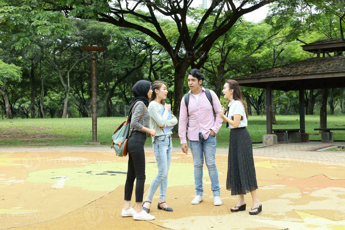 Young asian malay chinese man woman outdoor park walk stand study talk discuss point laptop file book backpack mingle fun meet greet photo