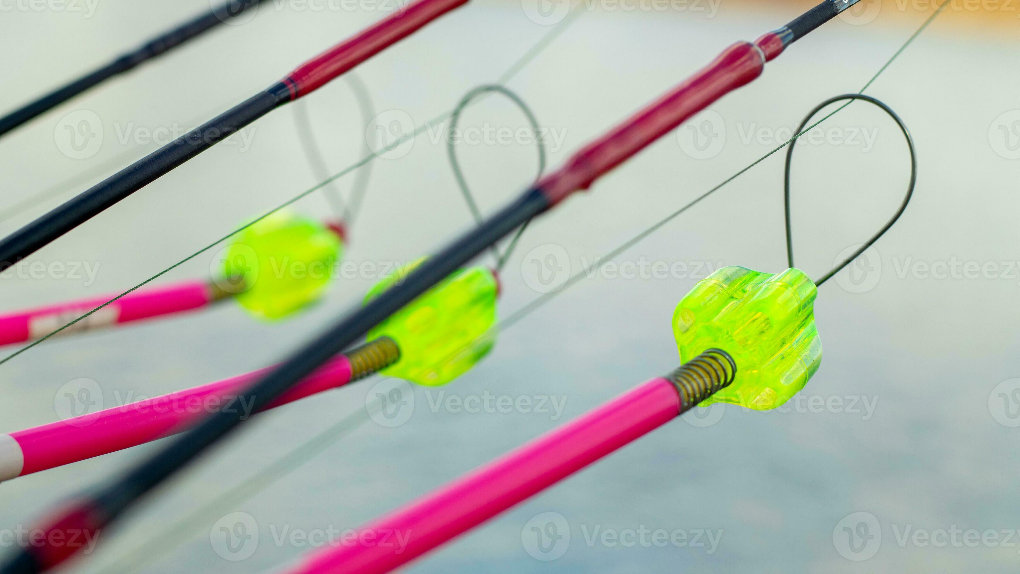 The bite alarm hangs on a fishing rod against the background of water. Fishing  rod while fishing on the lake, river. Fishing tackle. Carp rod on a stand  with a bite alarm