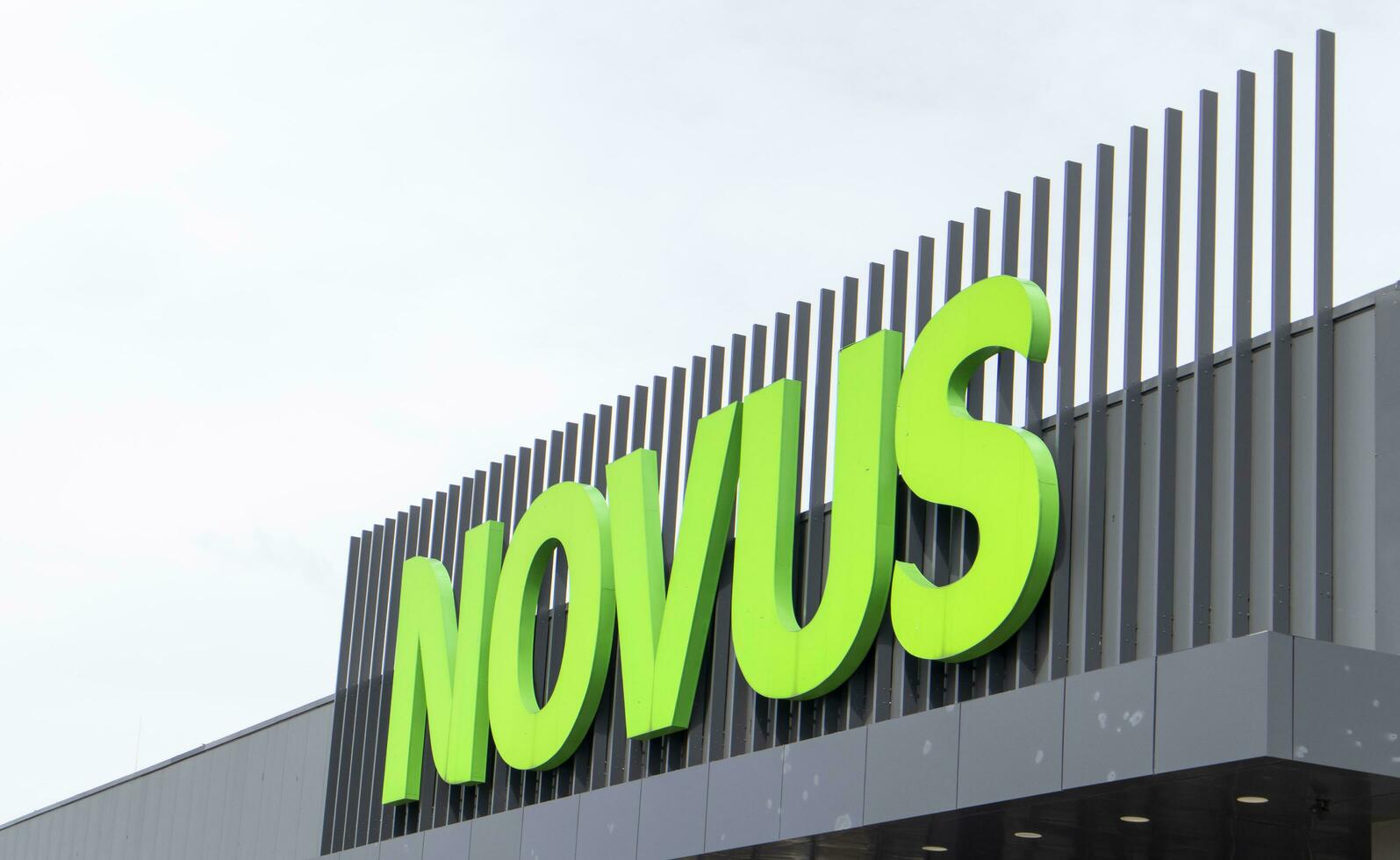 Ukrainian supermarket chain Novus. Green large signboard of the shopping center outside, on the street. Signboard against the sky. The building of the supermarket. Ukraine, Kyiv - May 01, 2023. photo