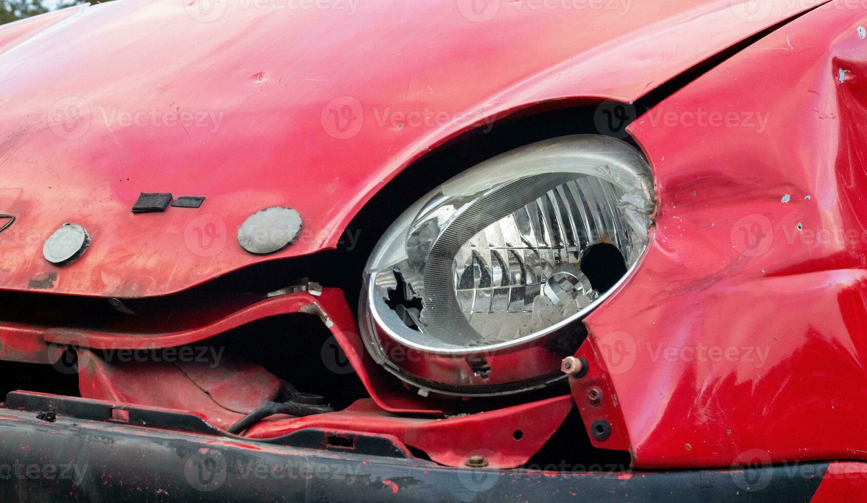 Broken headlight of a red car after a severe accident with a skewed body, after a powerful impact on the side of the road. Traffic accident on the street, damaged car after a collision in the city. photo