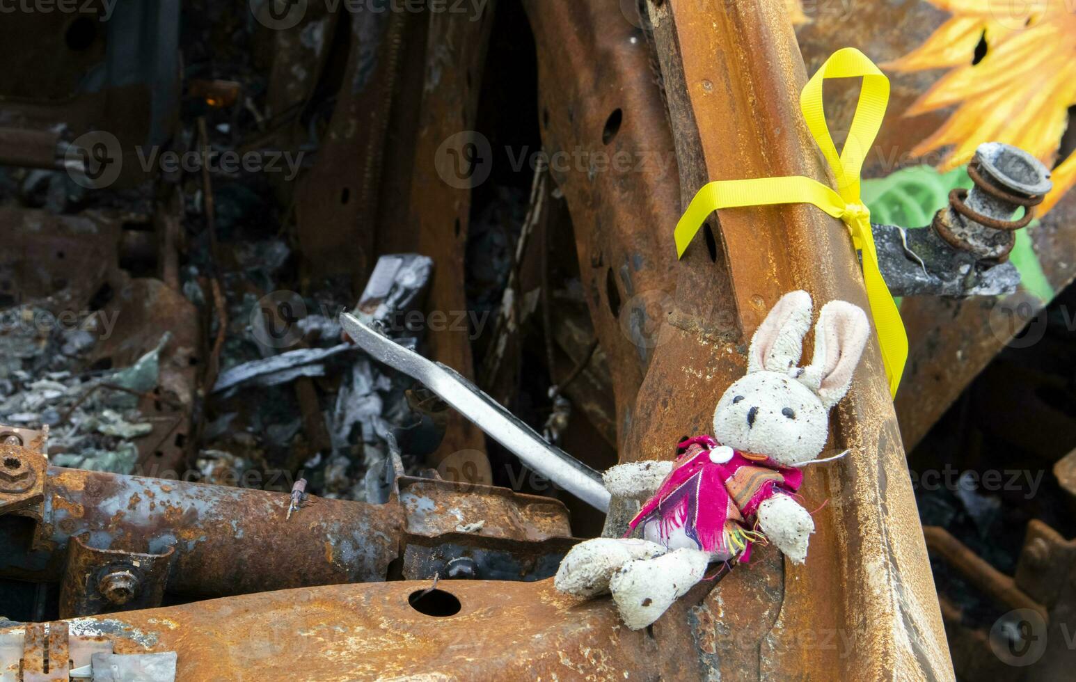 Close-up of a child's toy in ruins after a fire. A soft toy among a burned-out car. Spoiled childhood. The concept of a disaster with the death of a child. Dangerous traffic accident. photo