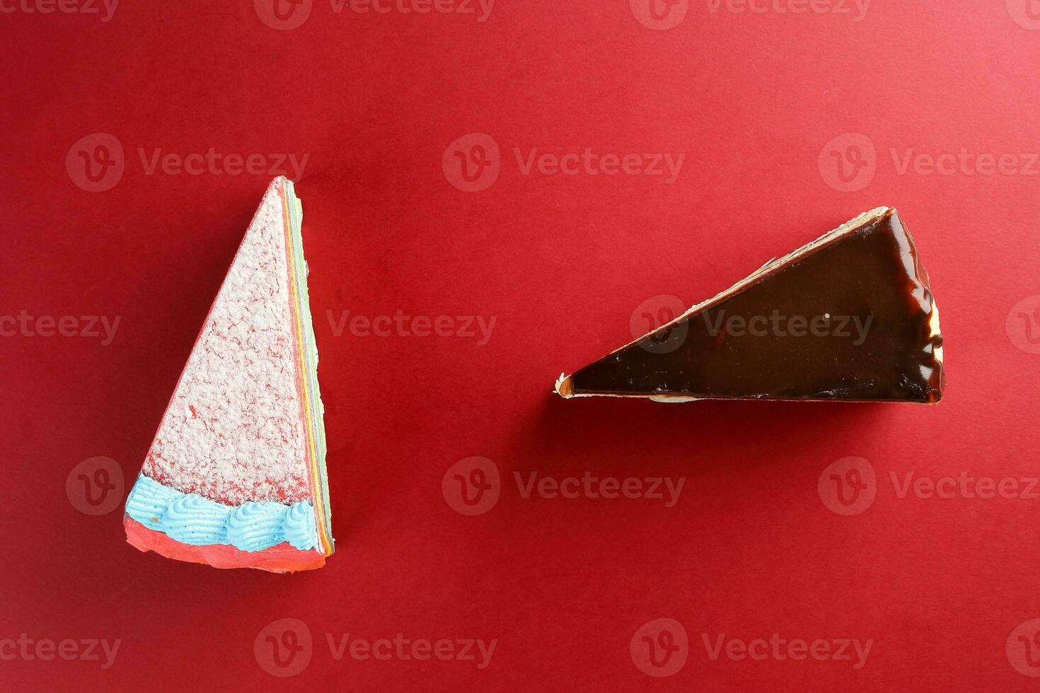 Rainbow Chocolate crepe layer cake two slice top view red background copy space photo