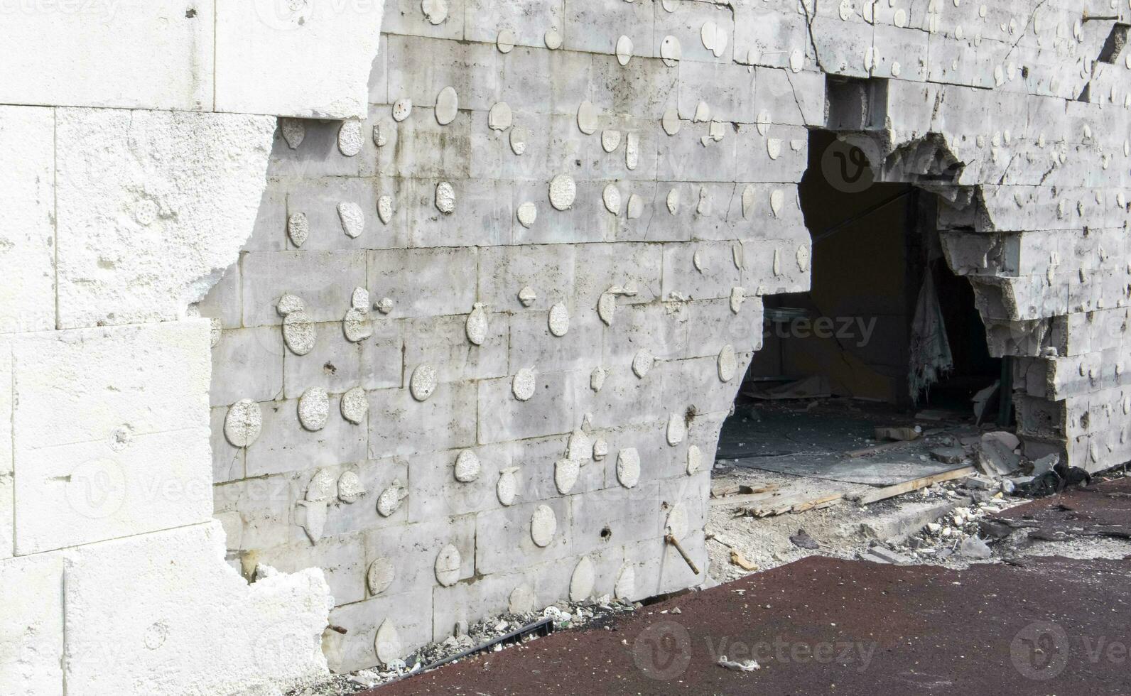 The wall of a building battered by rocket fragments in a war zone. Shelled wall. Facade of a bombed-out building. Armed conflict in Ukraine. Damage to the house as a result of artillery shelling. photo