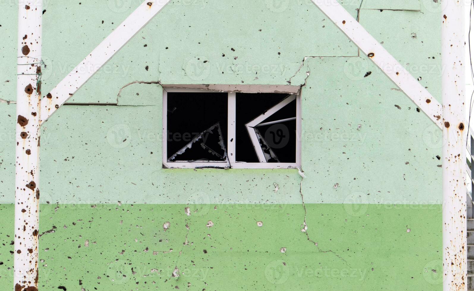 The wall of a building battered by rocket fragments in a war zone. Shelled wall. Facade of a bombed-out building. Armed conflict in Ukraine. Damage to the house as a result of artillery shelling. photo