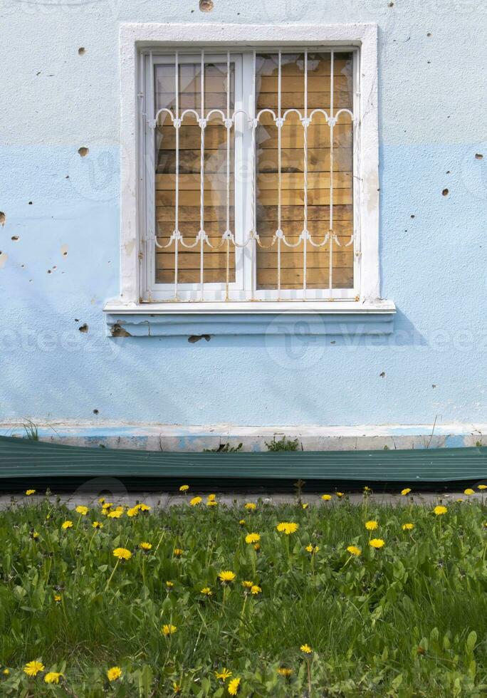 The buildings were hit by shelling. Boarded up windows and damaged facade. Preparing the house for hostilities and war. Destroyed houses in the city during the war in Ukraine. photo