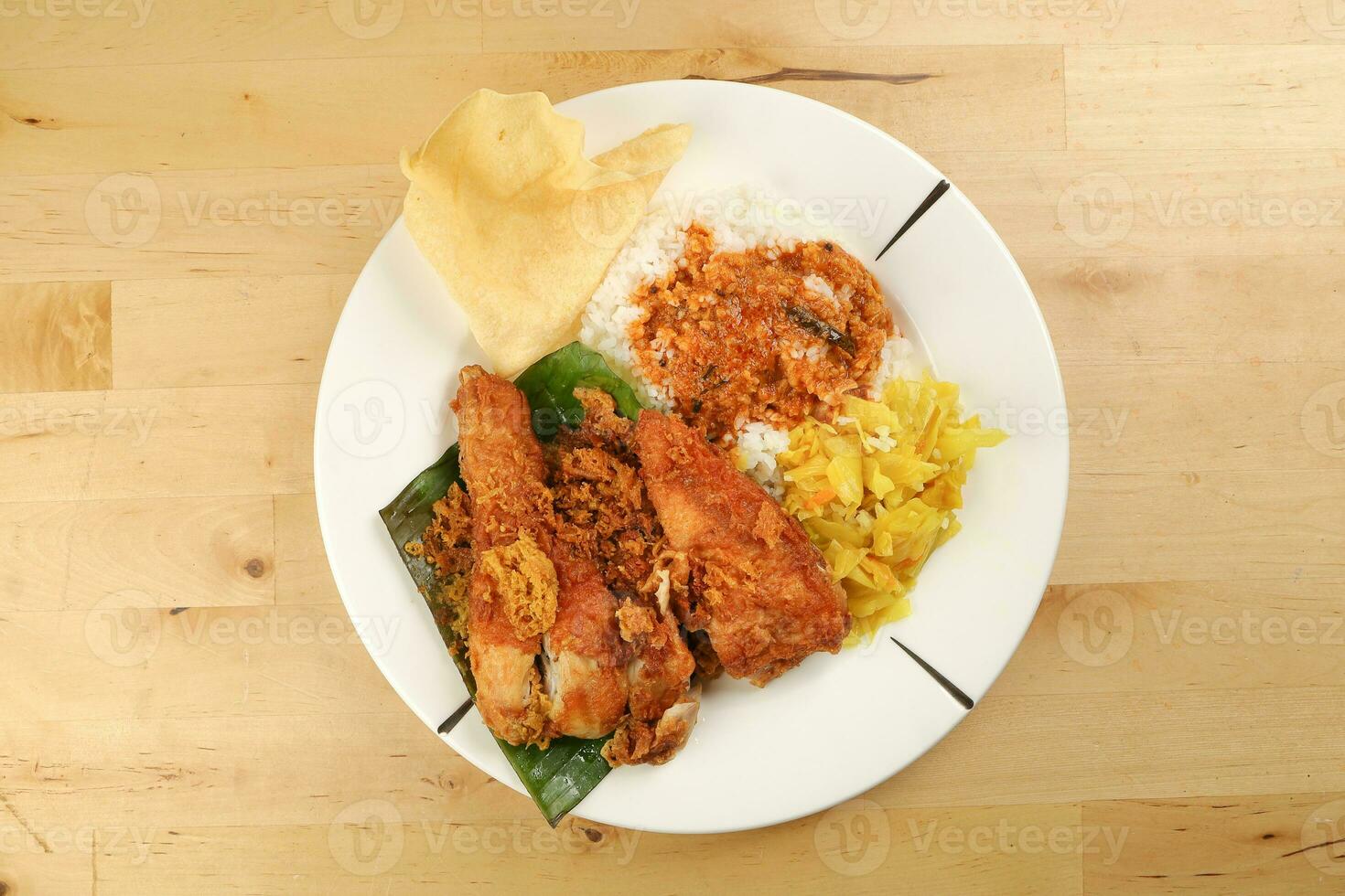 Traditional Malaysian Indian food white rice cabbage vegetable meat deep fried chopped chicken leg topped up with spicy mix gravy wood table background photo