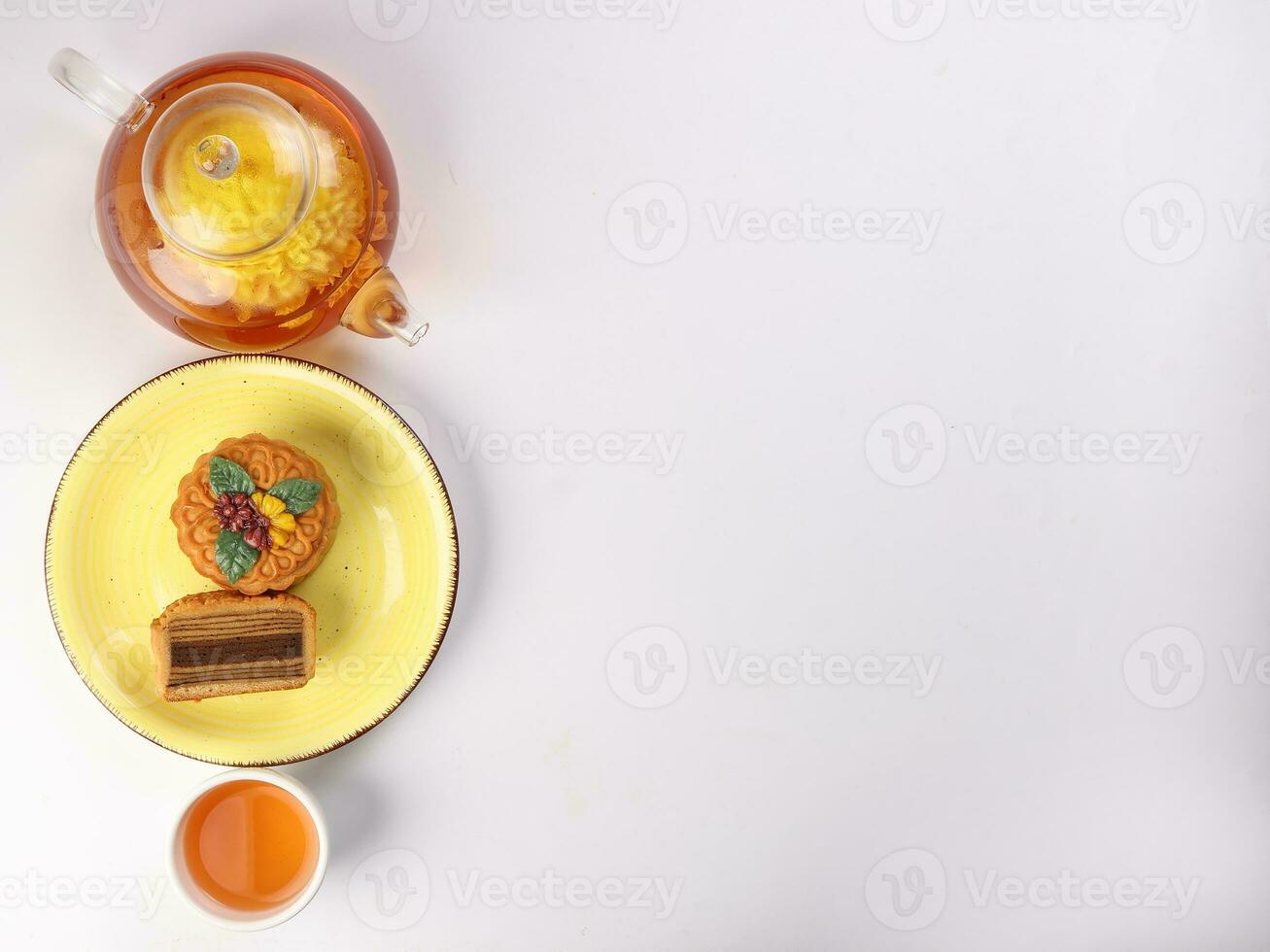 Colourful flower decorated mooncake Chinese mid autumn festival on bamboo food mat white background slice cut piece layered on yellow ceramic plate glass teapot teacup top view photo