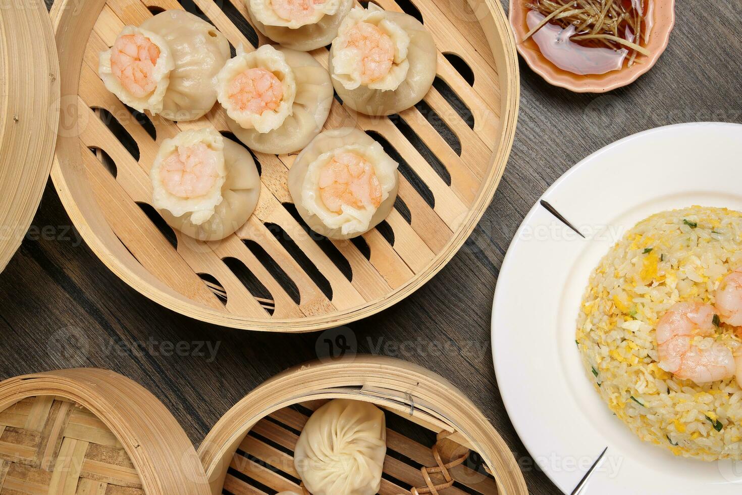 Prawn shrimp shaomai Xiao long bao dim sum dumpling chicken prawn fish seafood vegetable in bamboo steamer fried rice on plate sauce chopsticks soup spoon over rustic background photo