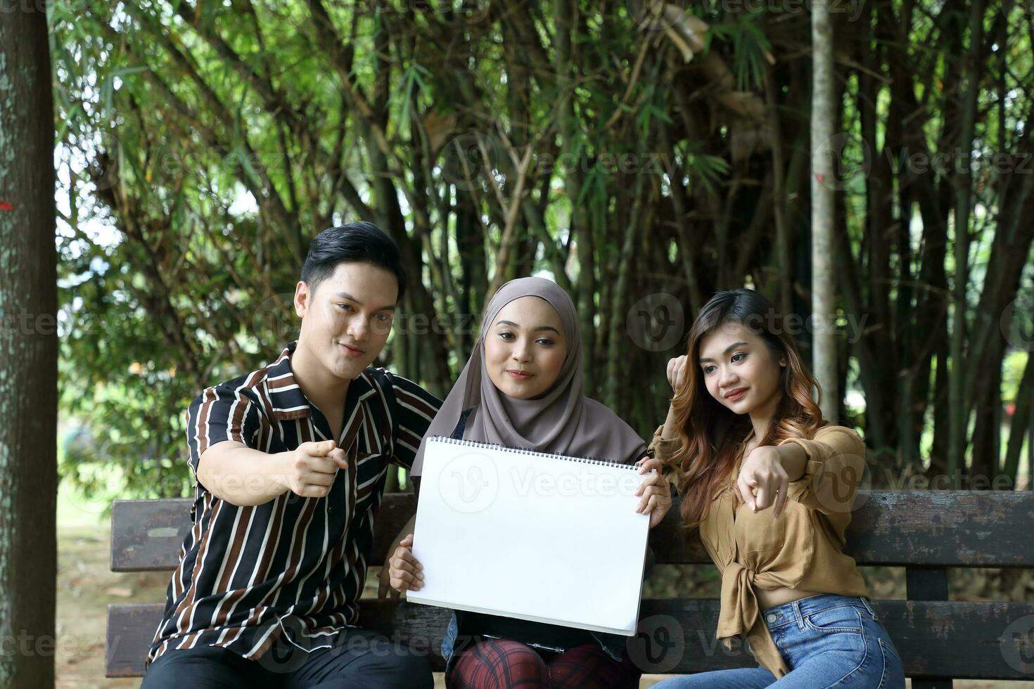 Young Asian Malay man woman outdoor green park walk talk discuss mingle photo