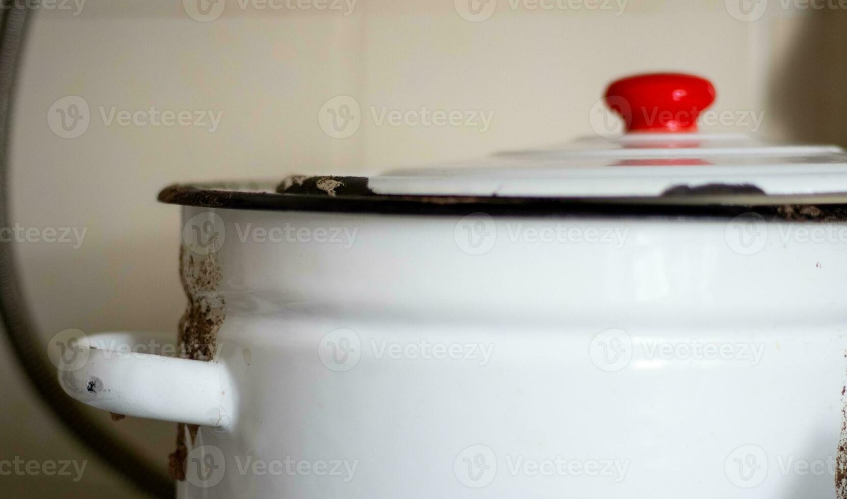 One large white pot with a lid and a red handle sits on a tile in a restaurant or home kitchen. photo