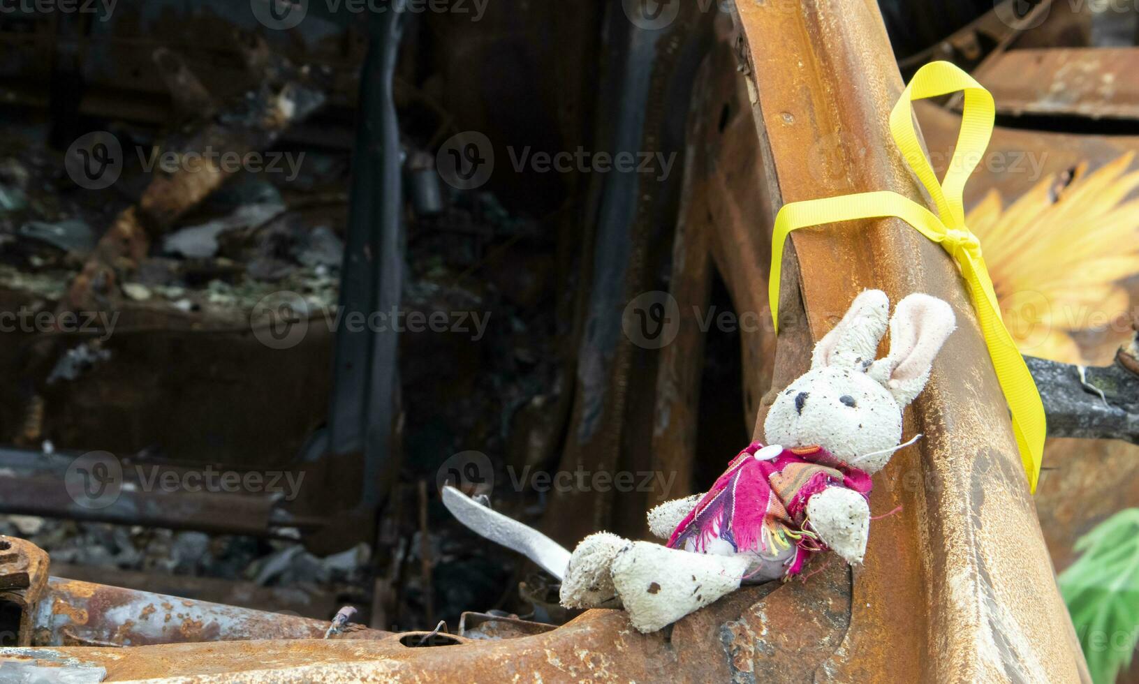Close-up of a child's toy in ruins after a fire. A soft toy among the cars that burned down as a result of the bombing. A ruined childhood. War concept. Ukraine. Dangerous traffic accident. photo