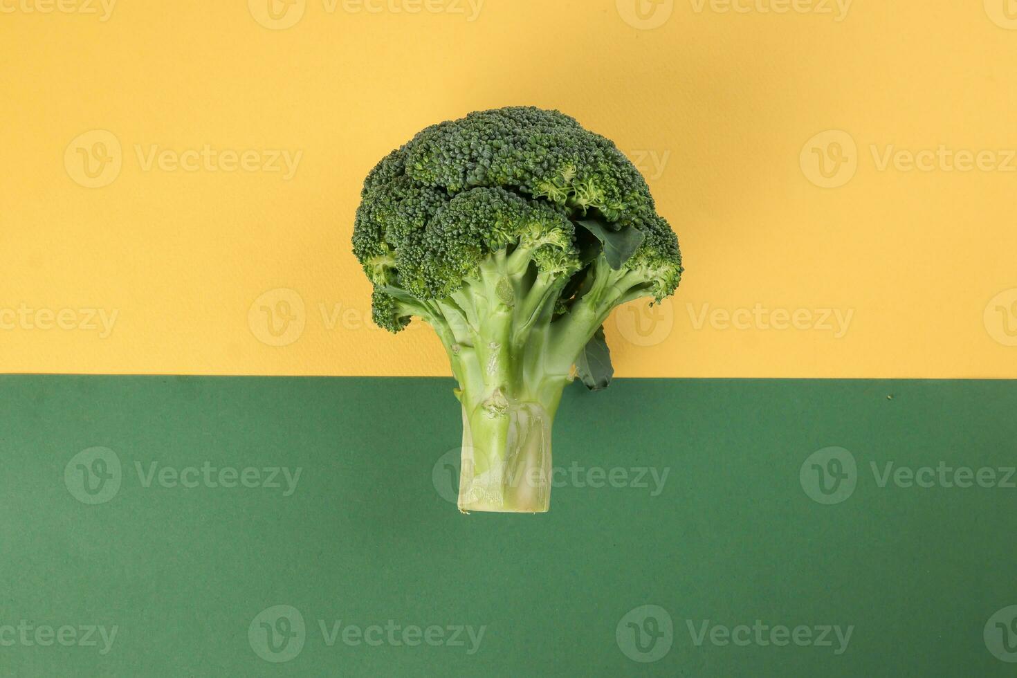 whole green broccoli closeup on yellow green background photo