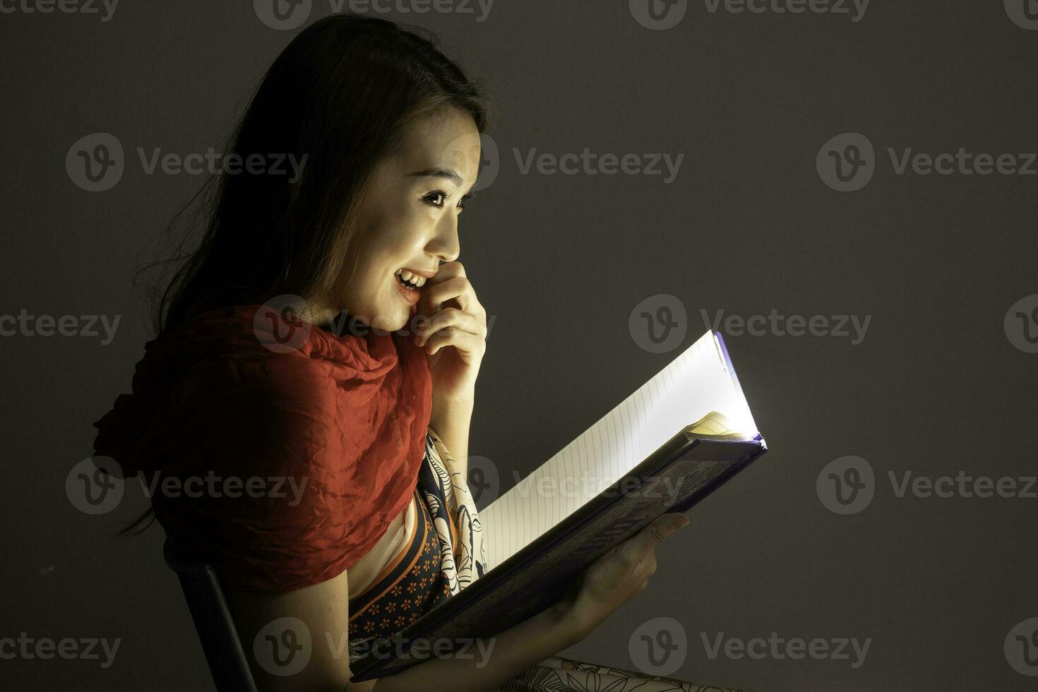 Asian woman opening mystic book box magical light dark background photo