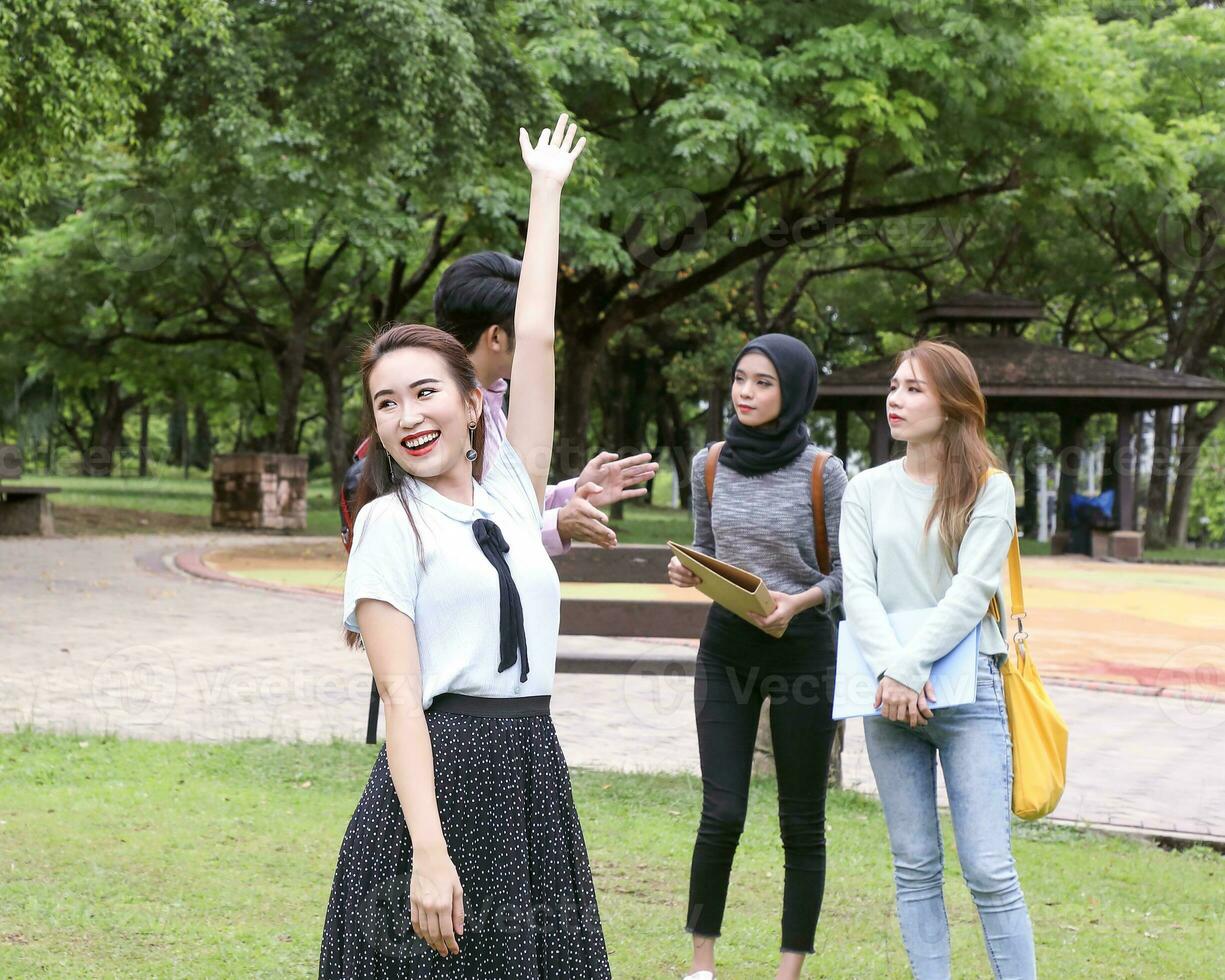 Young asian malay chinese man woman outdoor park walk stand study talk discuss point laptop file book backpack female look forward hello smile photo