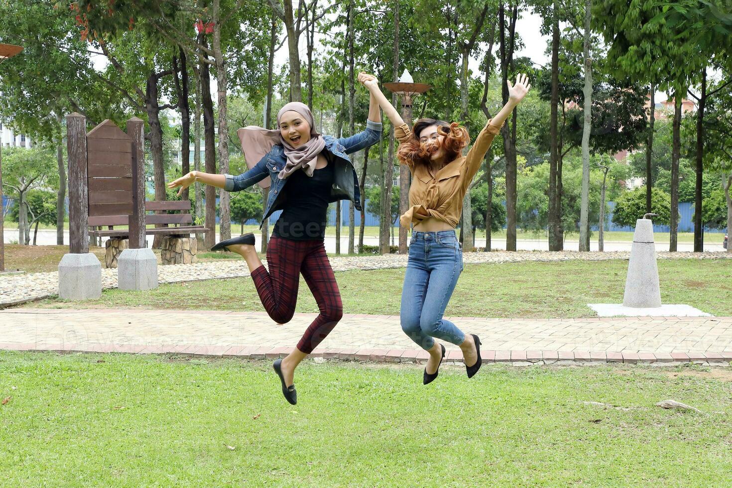 Young Asian Malay man woman outdoor green park joy happy jump in the air photo