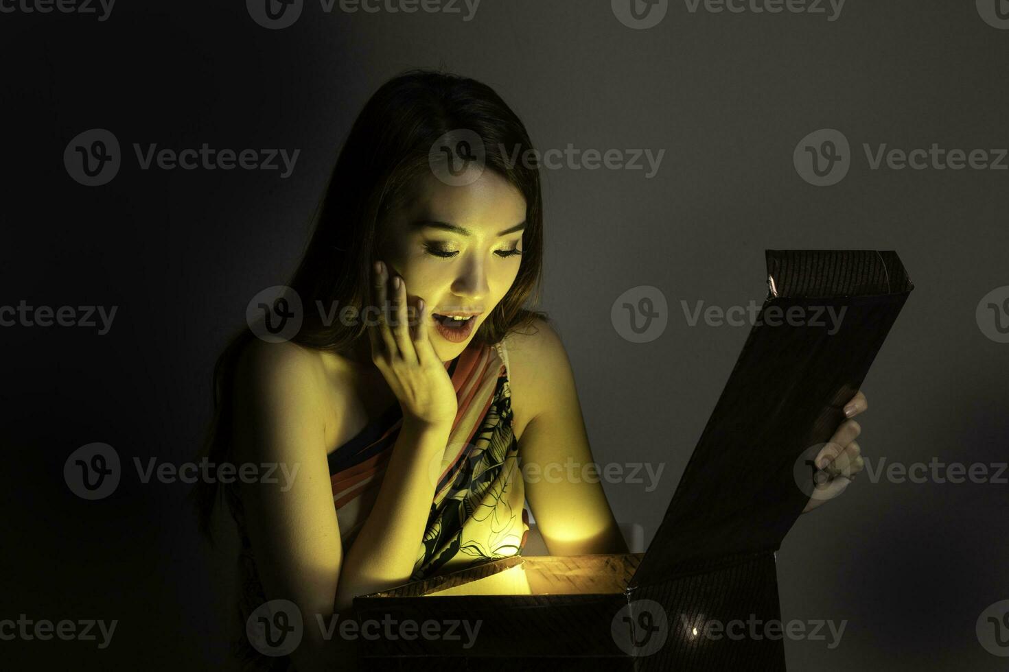 Asian woman opening mystic book box magical light dark background photo
