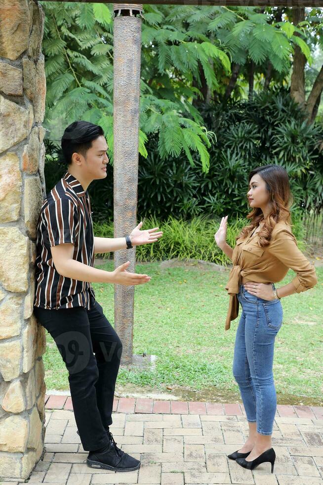 Young Asian Malay man woman couple outdoor green park talk discuss argue photo