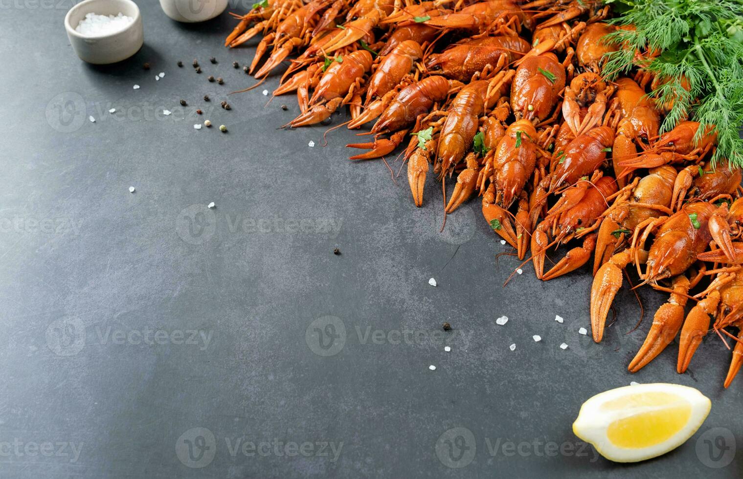 top view of cooked crawfish with lemons and spices on dark cement background photo