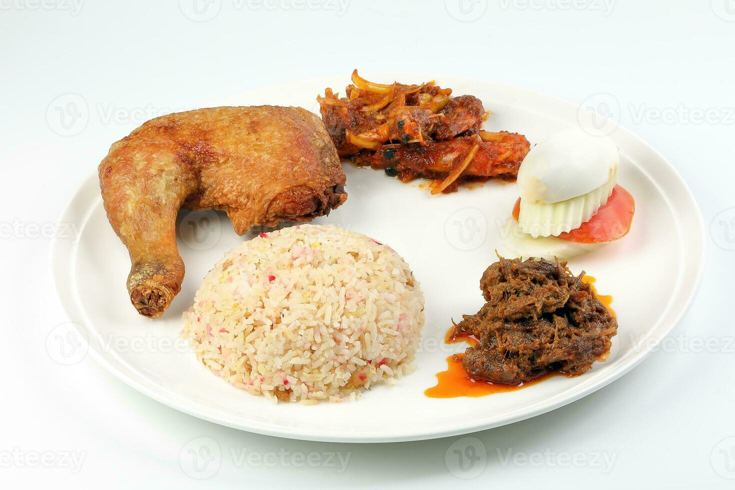 Indonesian royal dish nasi bojari with deep spiced deep fried chicken leg sambal prawn curry beef rendang boild egg cucumber and tomato slice photo
