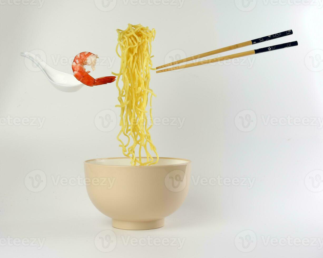Yellow seafood prawn noodle soup elevated flying suspended in air with soup spoon and chopstick on white background photo