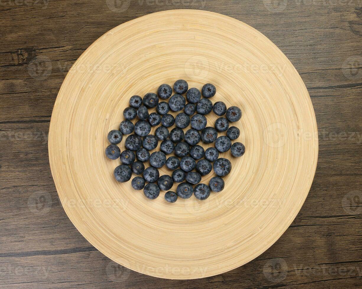 Fresh ripe deep purple Blueberry on old wooden plate macro closeup top view photo