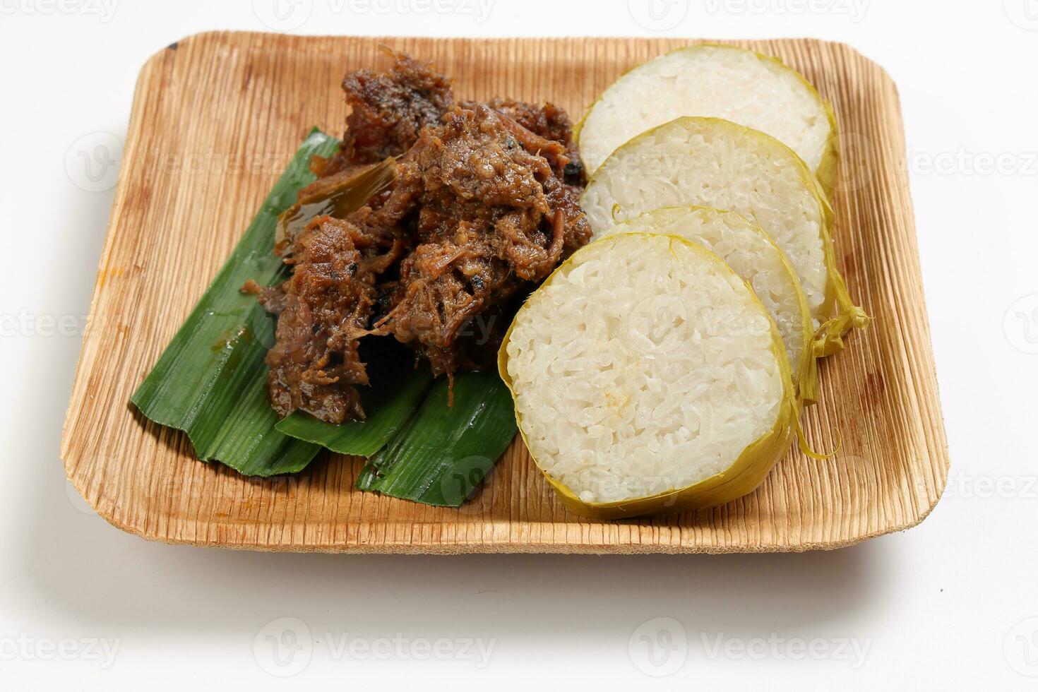 pulut lemang sticky rice steam cooked inside bamboo with beef rendang curry cooked sipce and coconut milk on palm leaf disposable square plate malay festival food photo