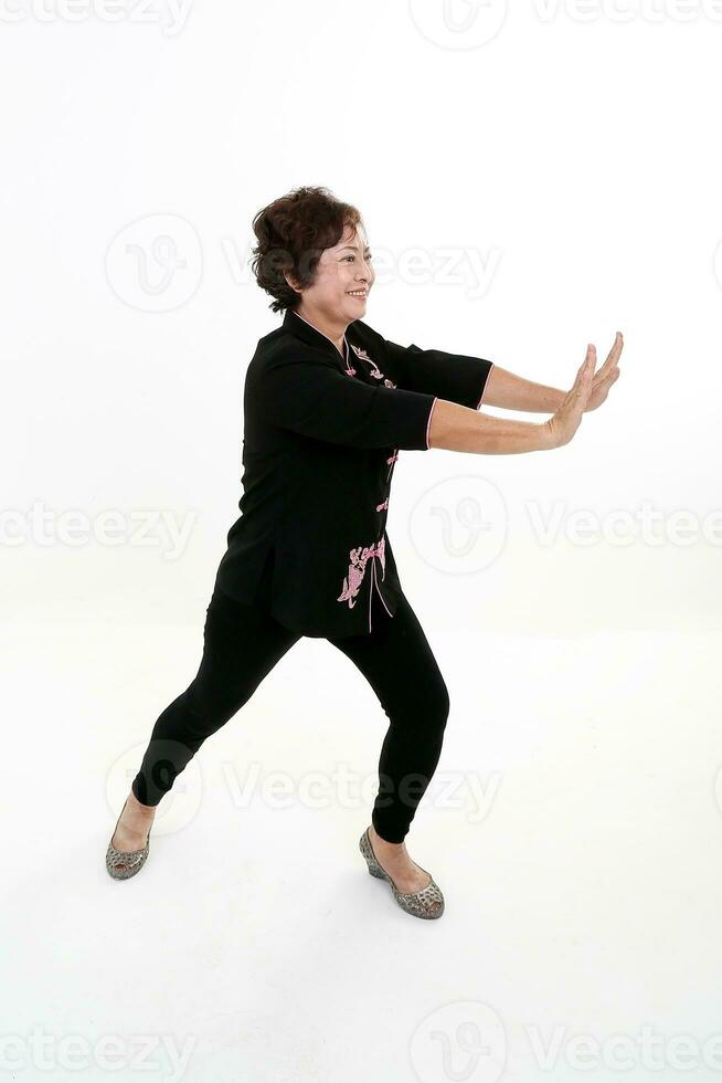 Elderly asian Chinese female wearing black tang samfu on white background exercise tai chi photo