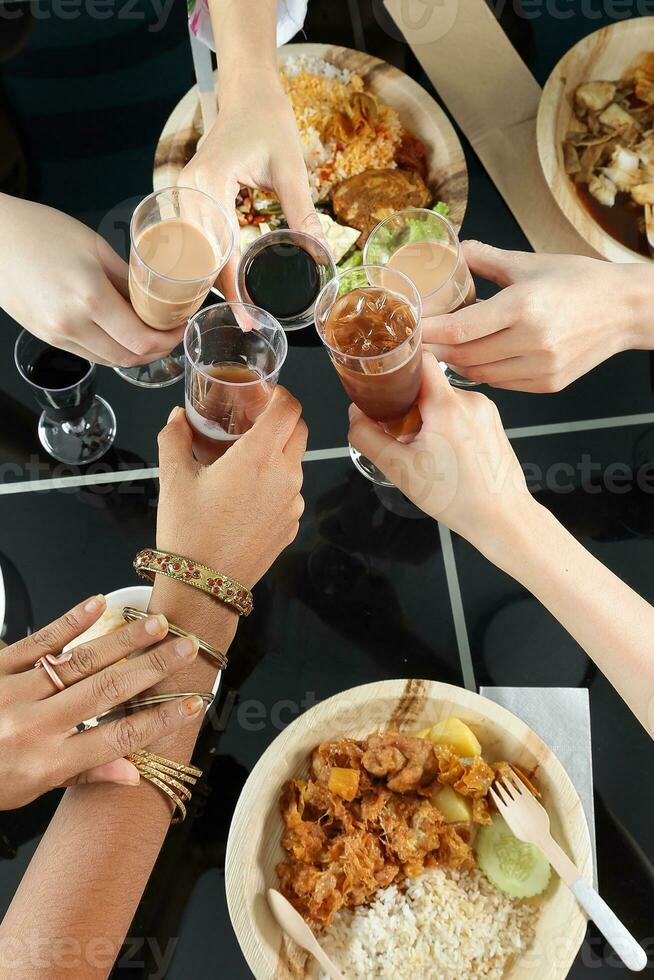 Young southeast asian woman group talk celebrate eating enjoying food rice curry noodle chicken drink cheers on dining table top view photo