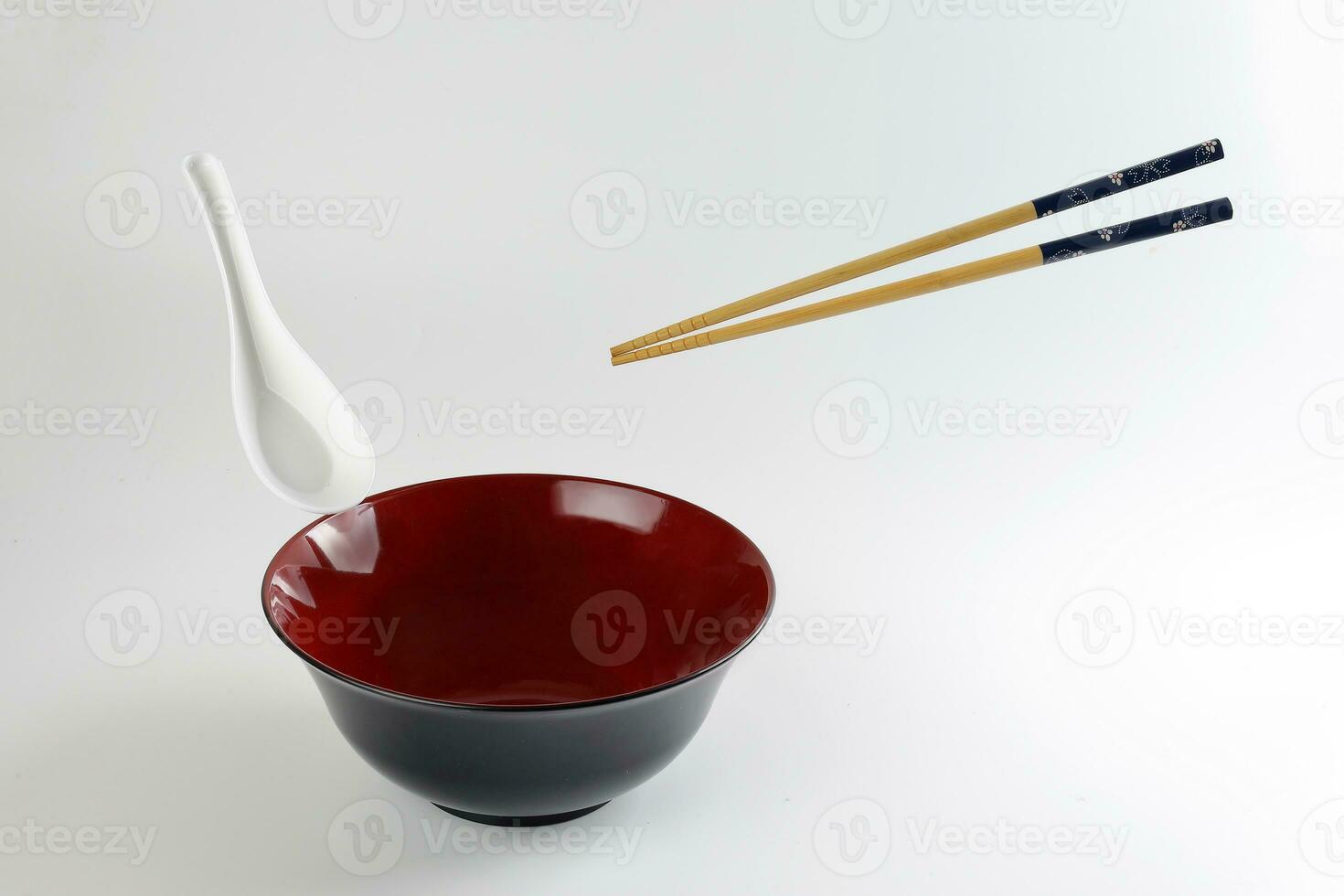 Empty oriental Japanese Chinese soup bowl spoon chopstick elevated flying in air red black white photo