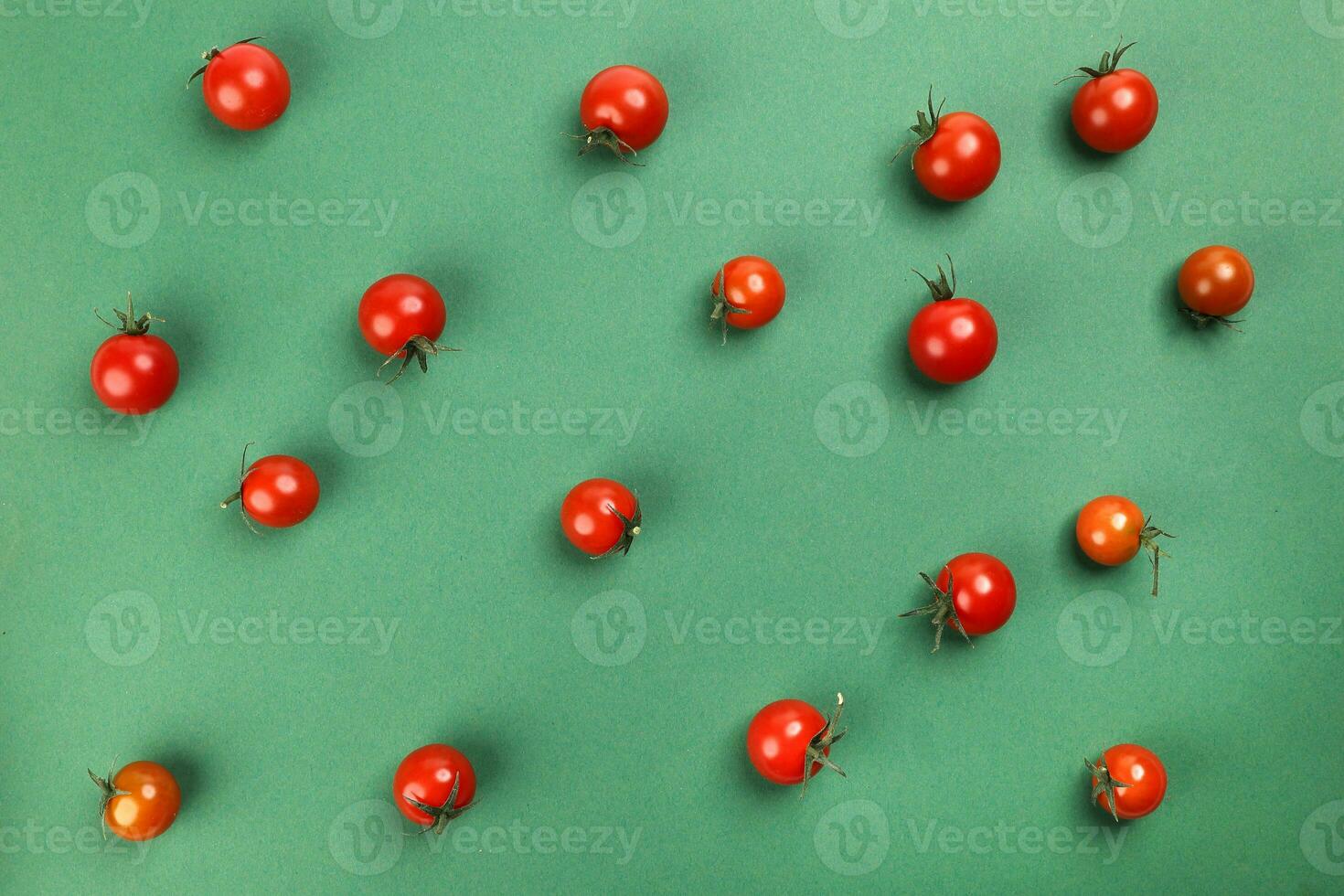 Red ripe cherry tomato with stem on green paper background copy text space photo