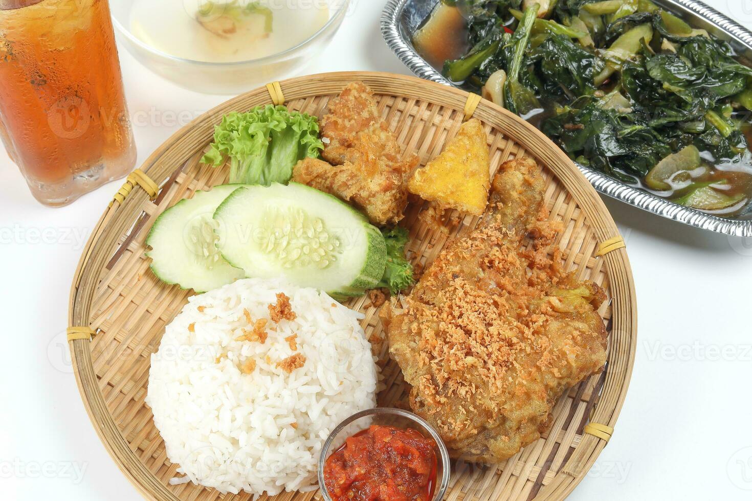 Ayam penyet East Javanese cuisine smashed fried chicken dish with floss sambal slices of cucumbers fried tofu and tempeh Stair fired green Chinese broccoli garlic oyster sauce ice lemon tea soup photo