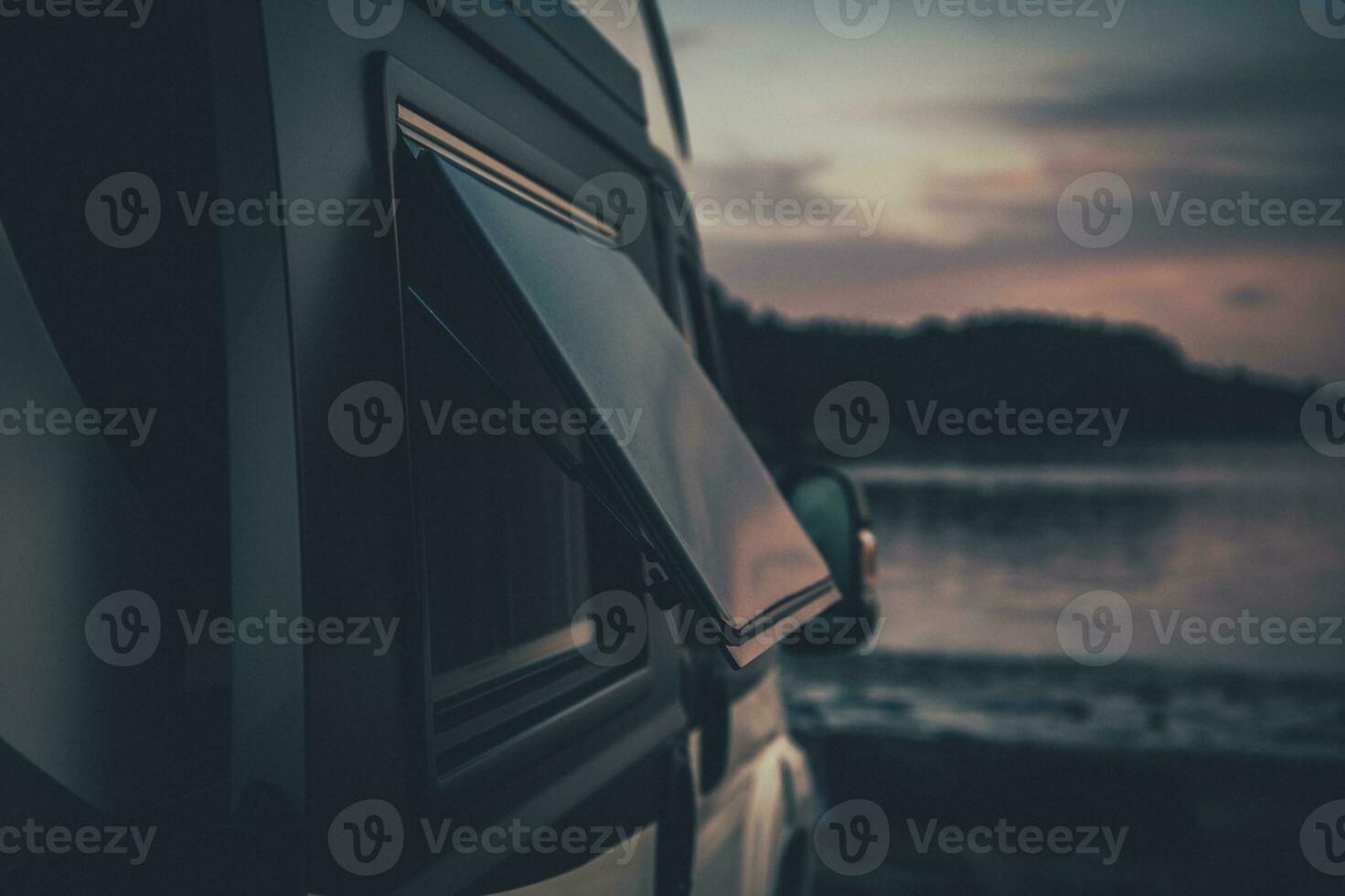 Camper with Tilted Window Parked on Shore photo