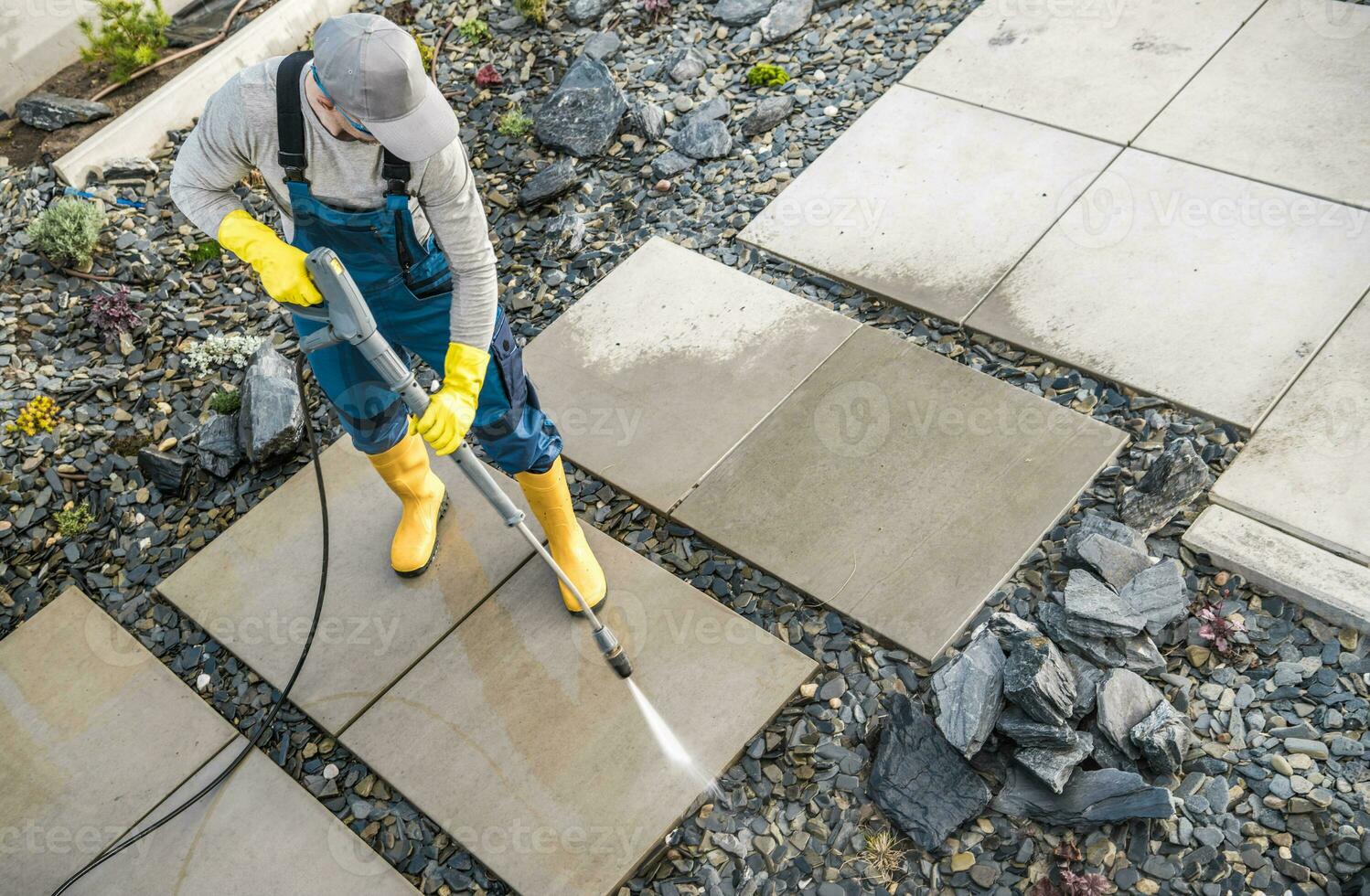 dueño de casa Lavado fuera suciedad desde su jardín hormigón rutas utilizando presión lavadora foto